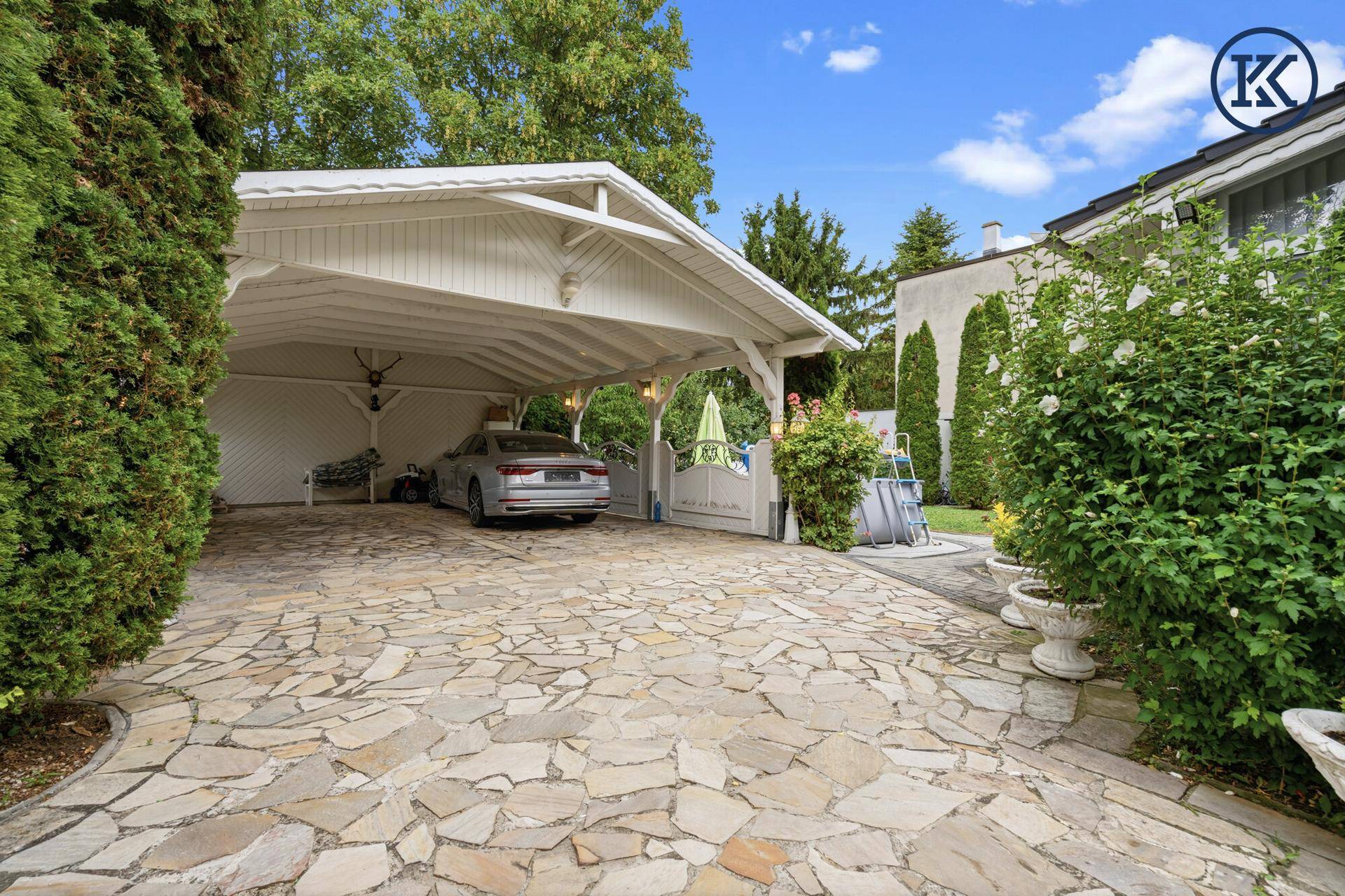 Geräumiger Carport mit gepflasterter Zufahrt und Platz für ein Fahrzeug.