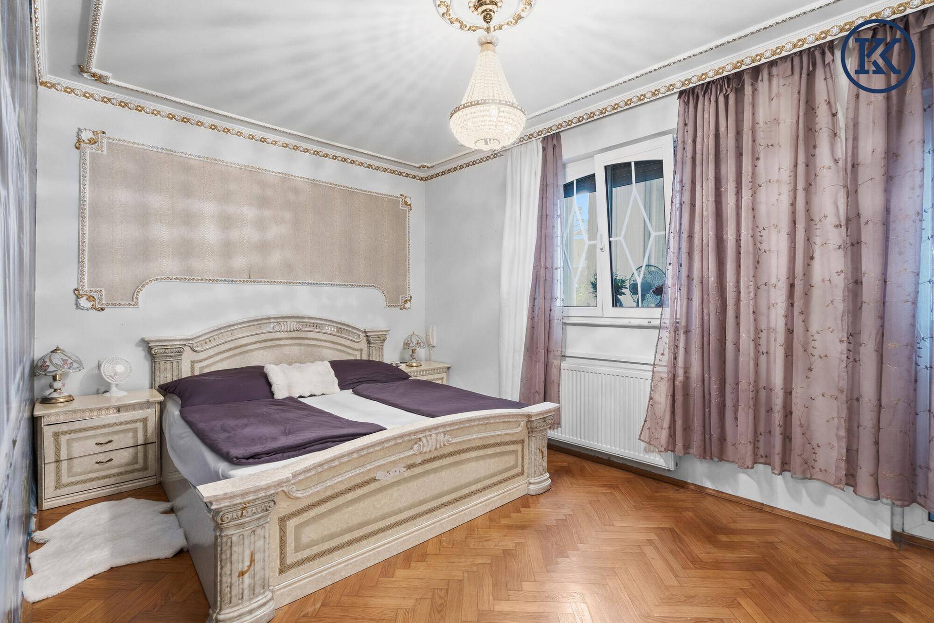 Schlafzimmer mit großem Bett, Parkettboden und opulenten Vorhängen.