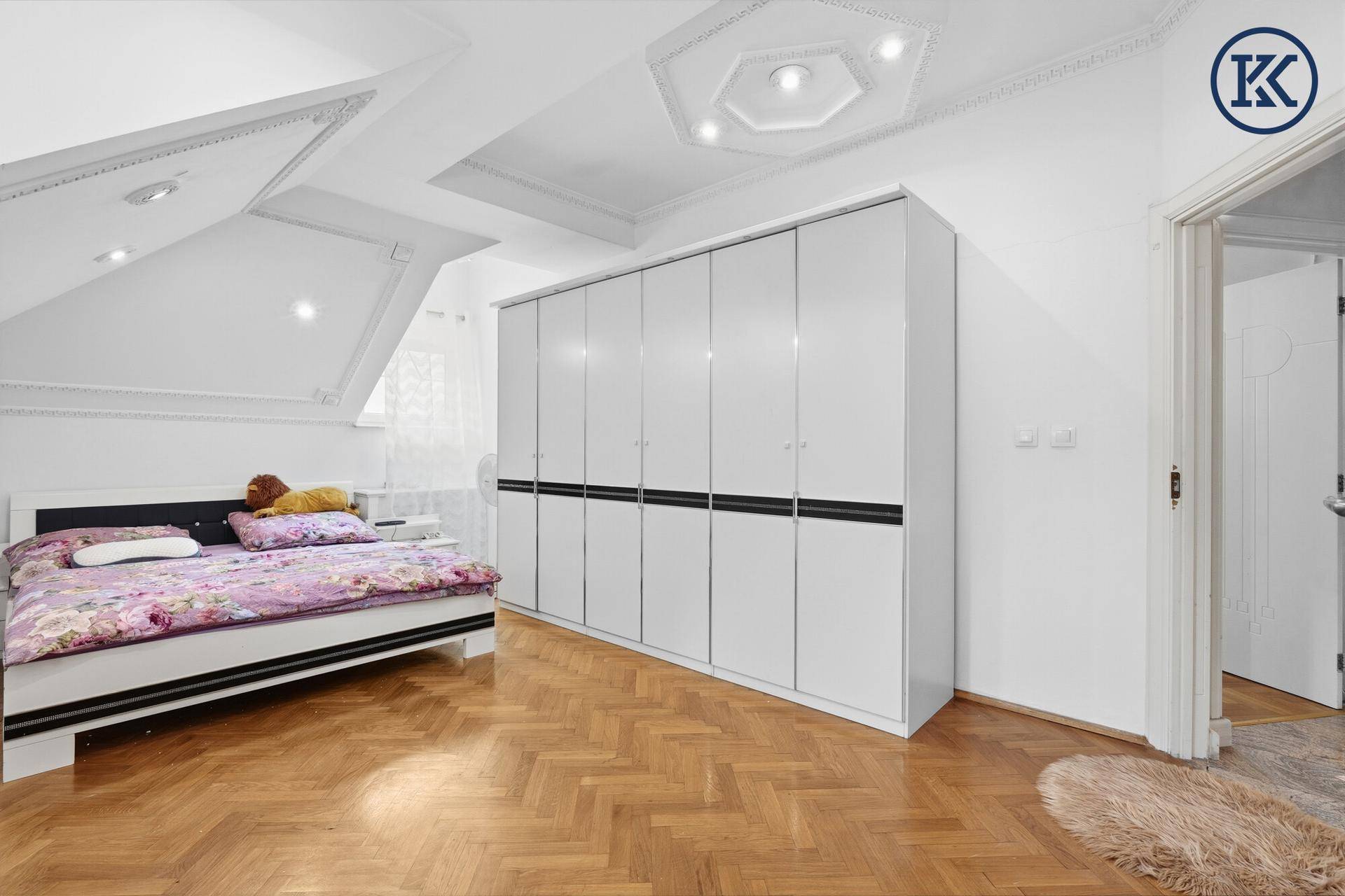 Schlafzimmer im Dachgeschoss mit großem Kleiderschrank, Parkettboden und Dachschrägen.