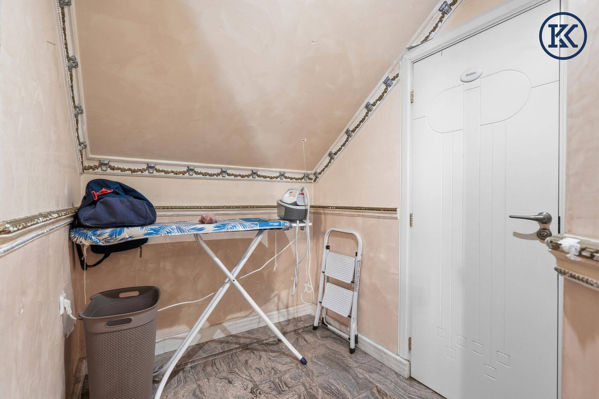 Praktischer Hauswirtschaftsraum im Dachgeschoss mit Bügelbrett und Stauraum.