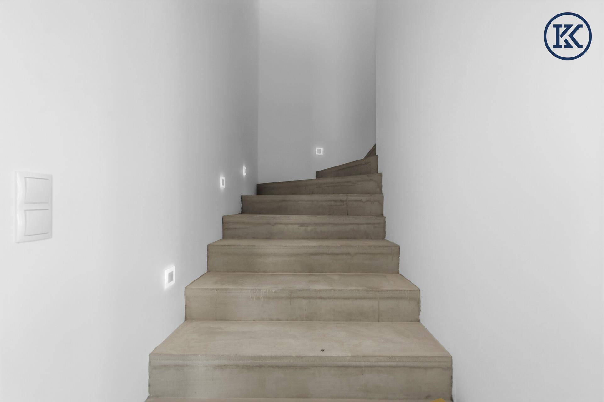 Moderne Betontreppe mit integrierter Beleuchtung, die in das obere Stockwerk führt.