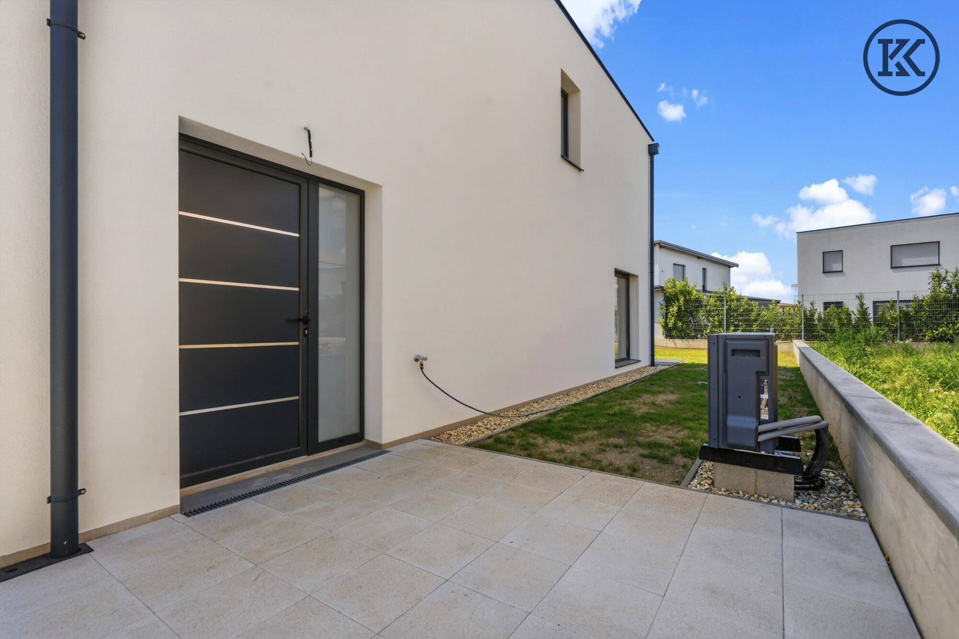 Kleine gepflasterte Terrasse neben dem Haus mit Zugang durch eine moderne Tür.