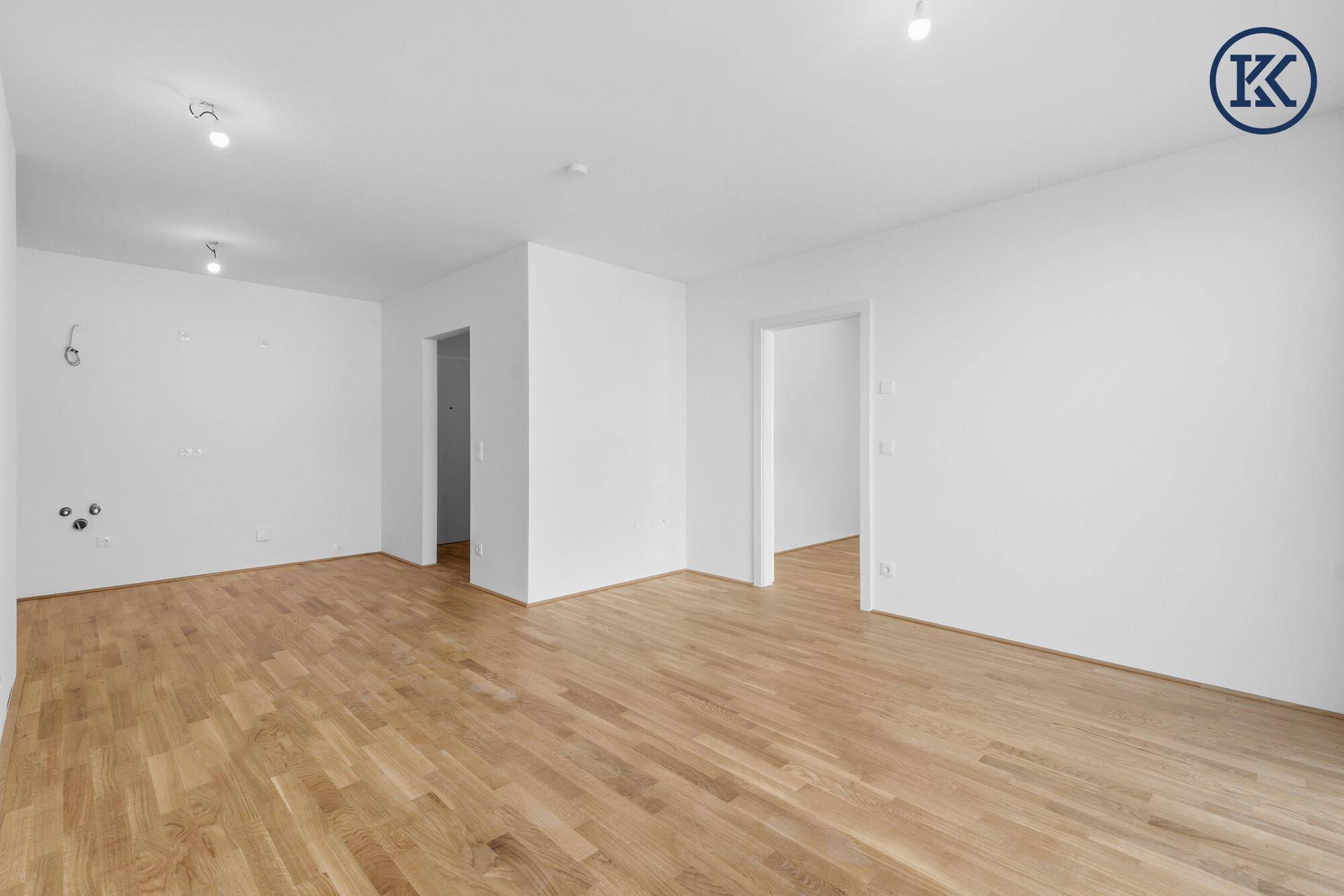 Geräumiges, leeres Wohnzimmer mit hellem Parkettboden und weißen Wänden, bereit zur individuellen Gestaltung.