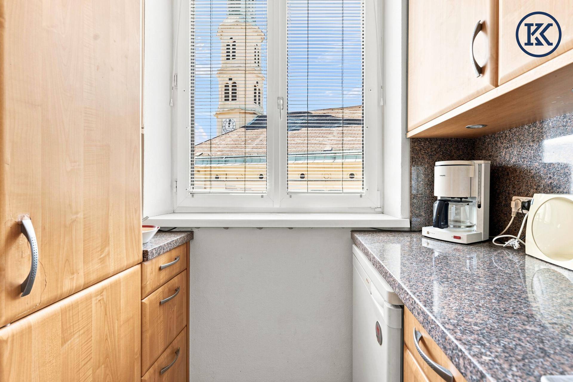 Küchenfenster mit Blick auf einen Kirchturm und die umliegenden Gebäude, das natürliches Licht spendet.