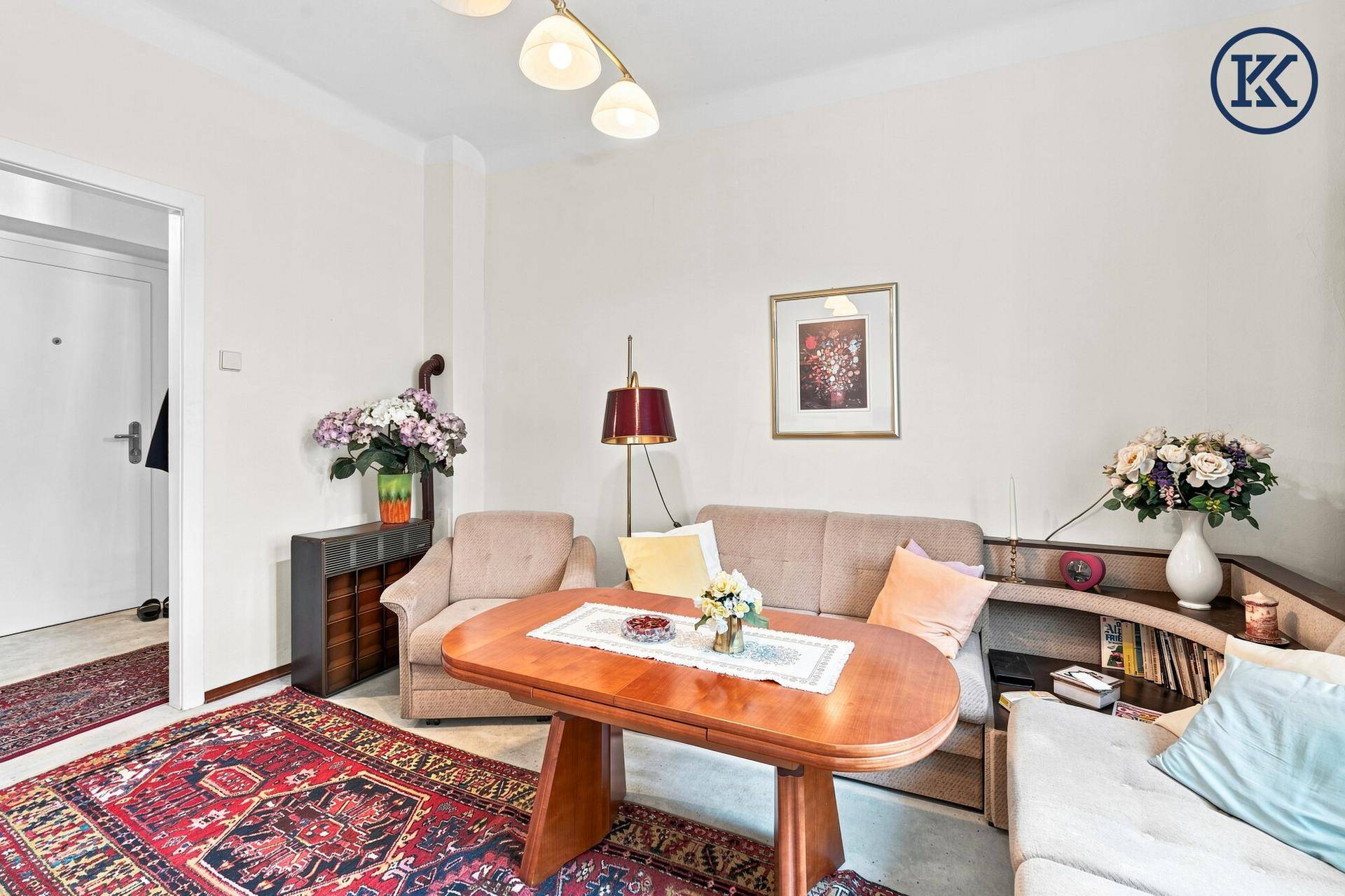 Wohnzimmer mit bequemen Sitzgelegenheiten, einem ovalen Holztisch und dekorativen Blumenarrangements.