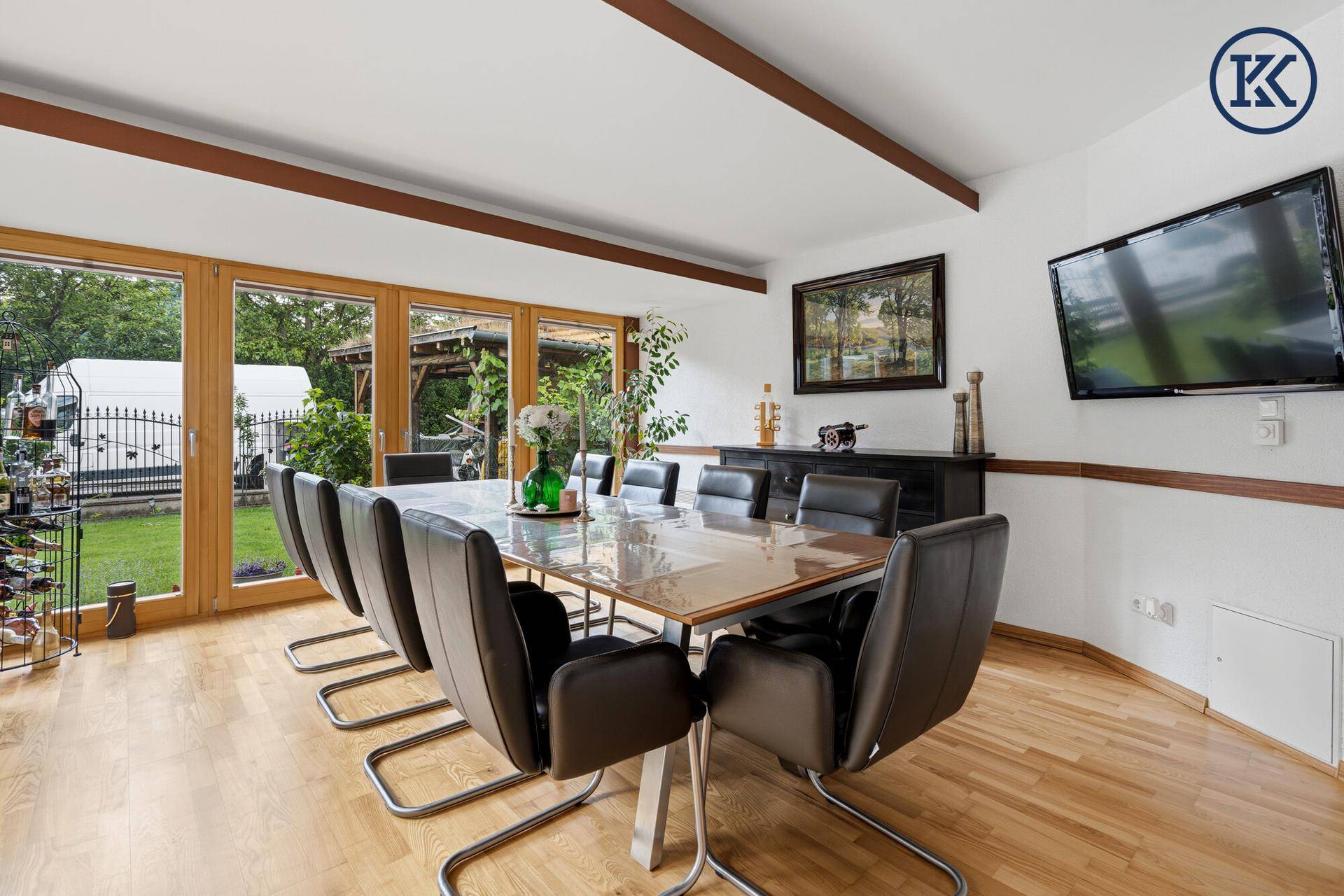 Heller Essbereich mit großem Tisch, Holzboden und Zugang zum Garten durch große Fenster.