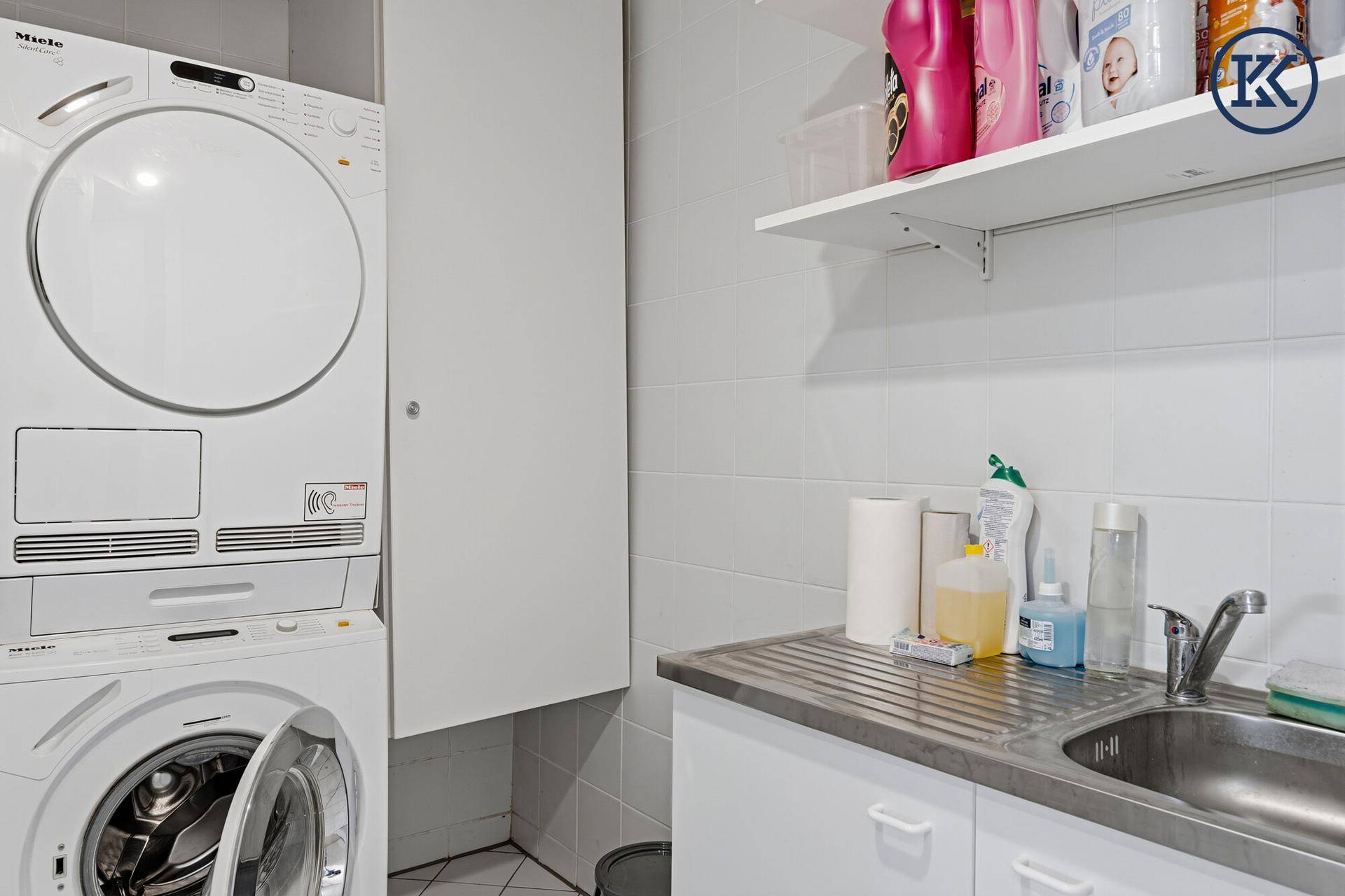 Praktischer Hauswirtschaftsraum mit Waschmaschine, Trockner und Spülbecken.
