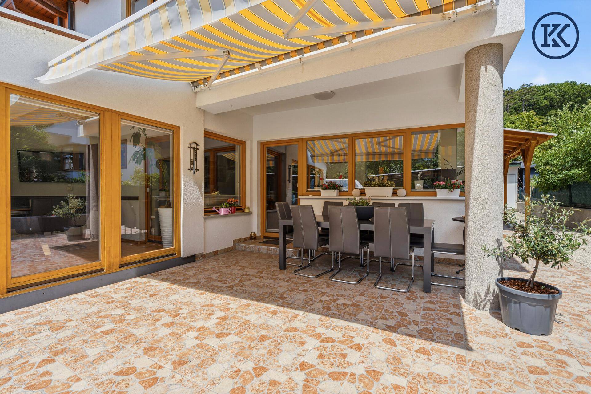Große, geflieste Terrasse mit Esstisch und Markise für sonnige Tage.