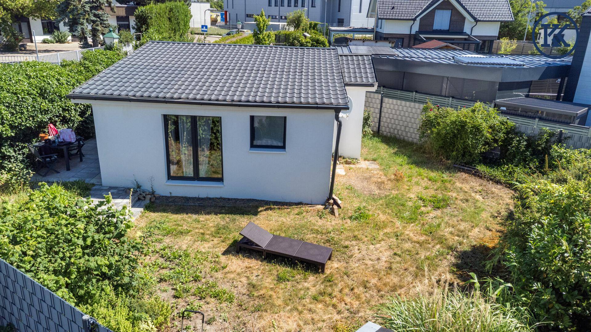 Luftaufnahme des kleinen Hauses mit Garten, Dach und umliegender Bebauung.