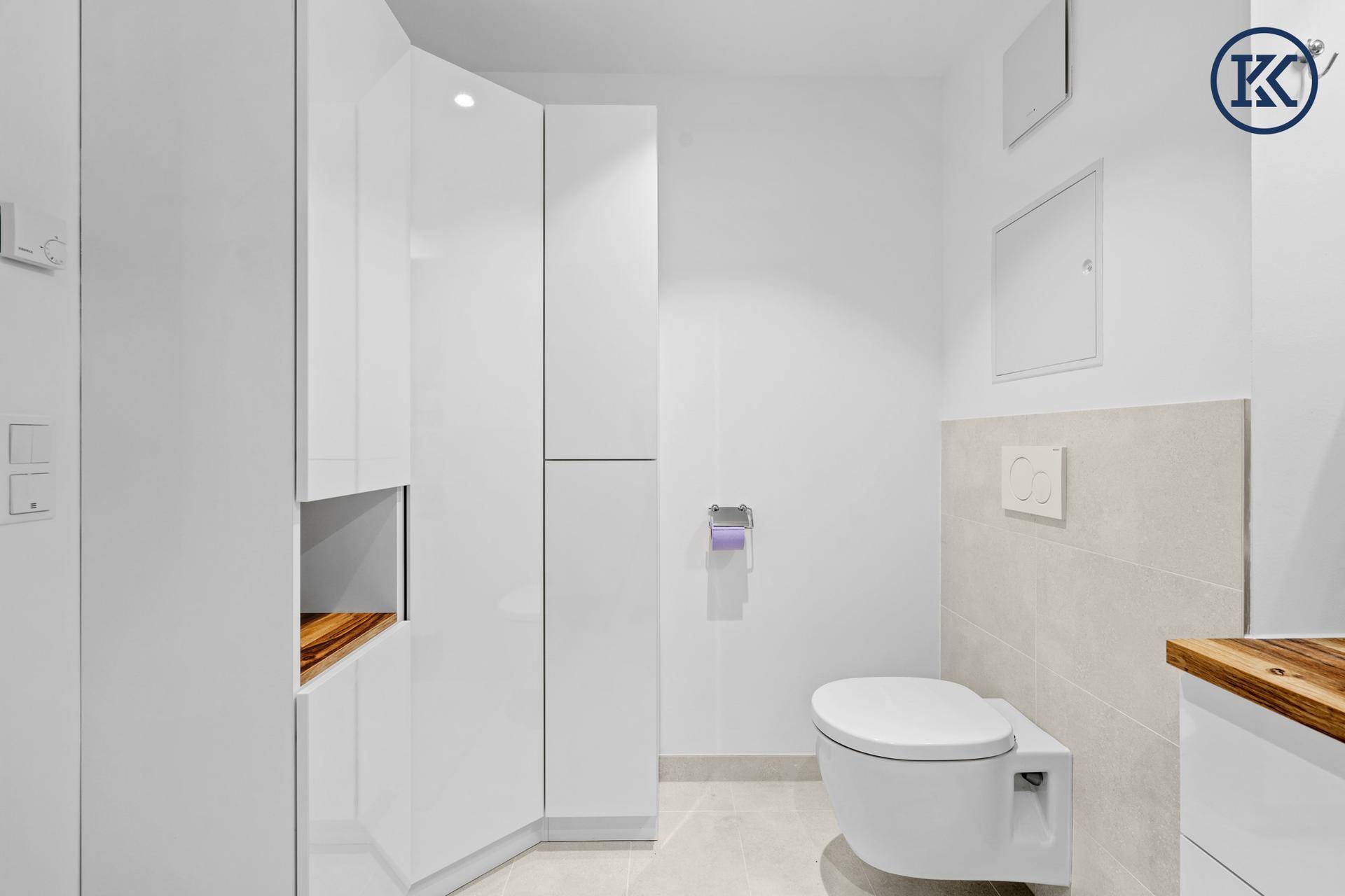 Helles WC mit wandhängender Toilette und praktischen, weißen Einbauschränken.