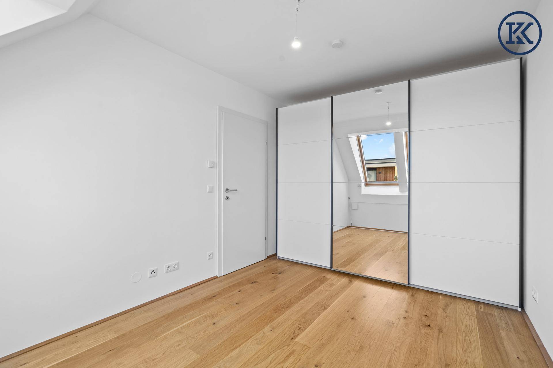 Schlafzimmer mit Holzboden und großem Spiegelschrank, der den Raum optisch vergrößert.