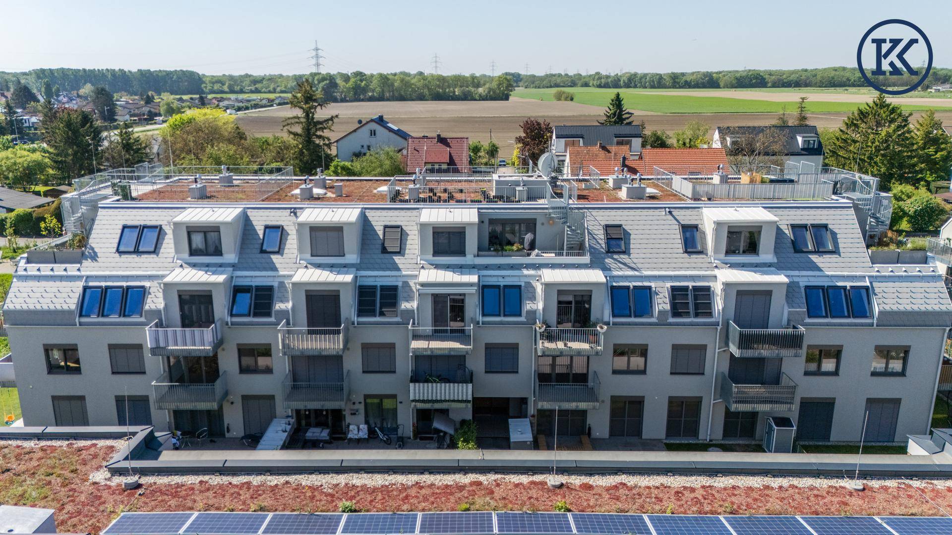 Ansicht der modernen Wohnanlage mit Dachterrassen und Solarpaneelen auf den Dächern.