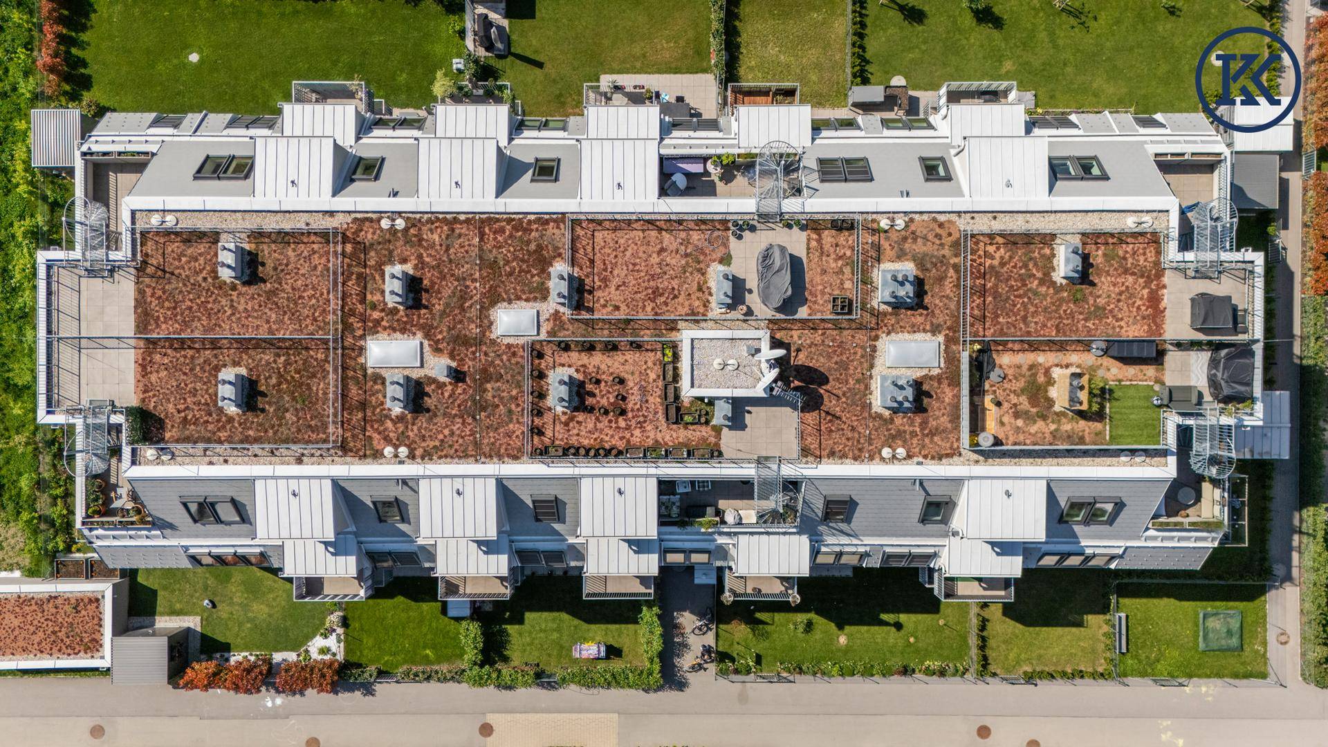 Vogelperspektive auf die Dächer einer Wohnanlage mit Dachterrassen und Gründächern.