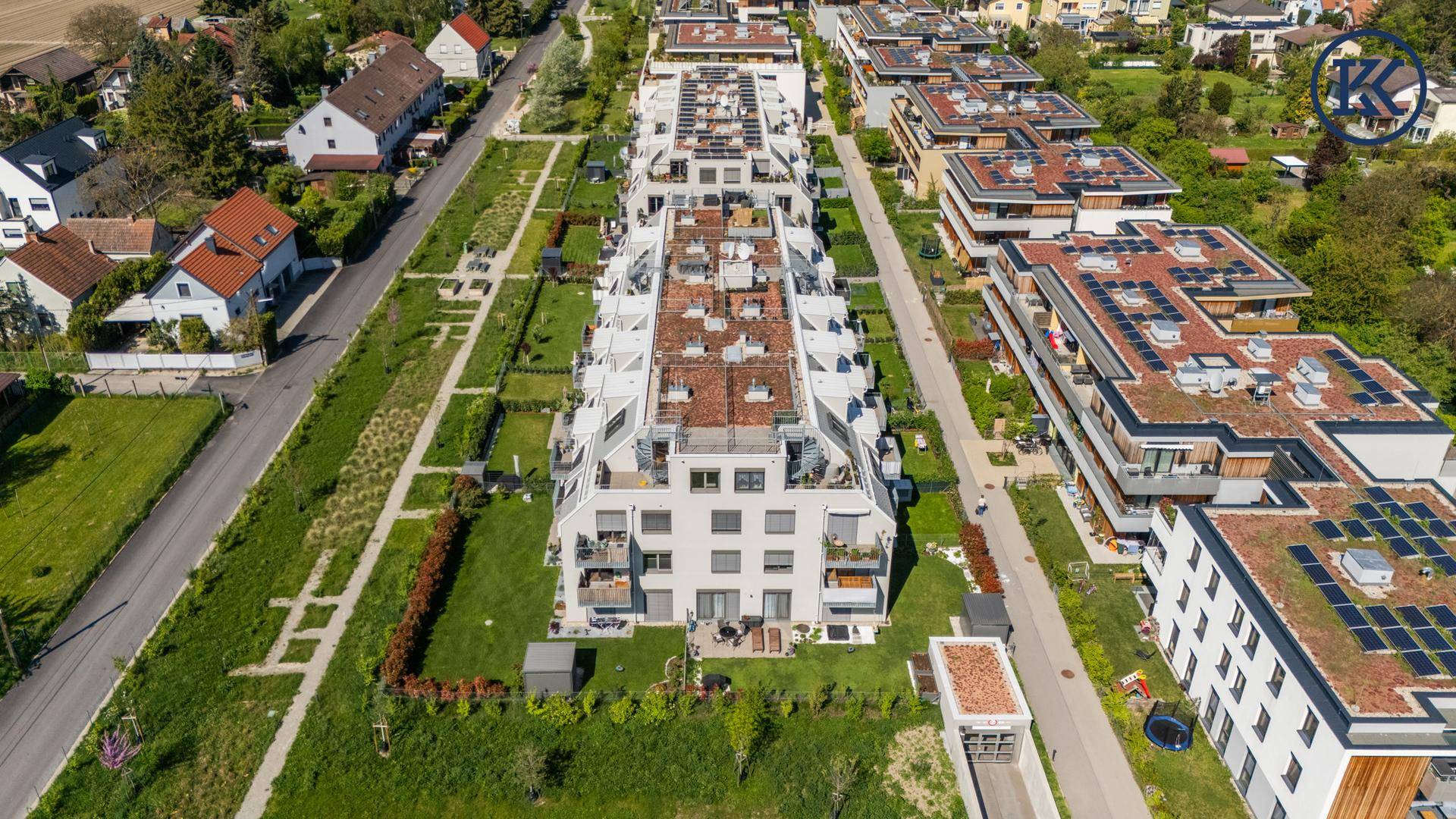 Weitläufige Wohnanlage mit modernen Gebäuden, Grünflächen und angrenzender ländlicher Umgebung.