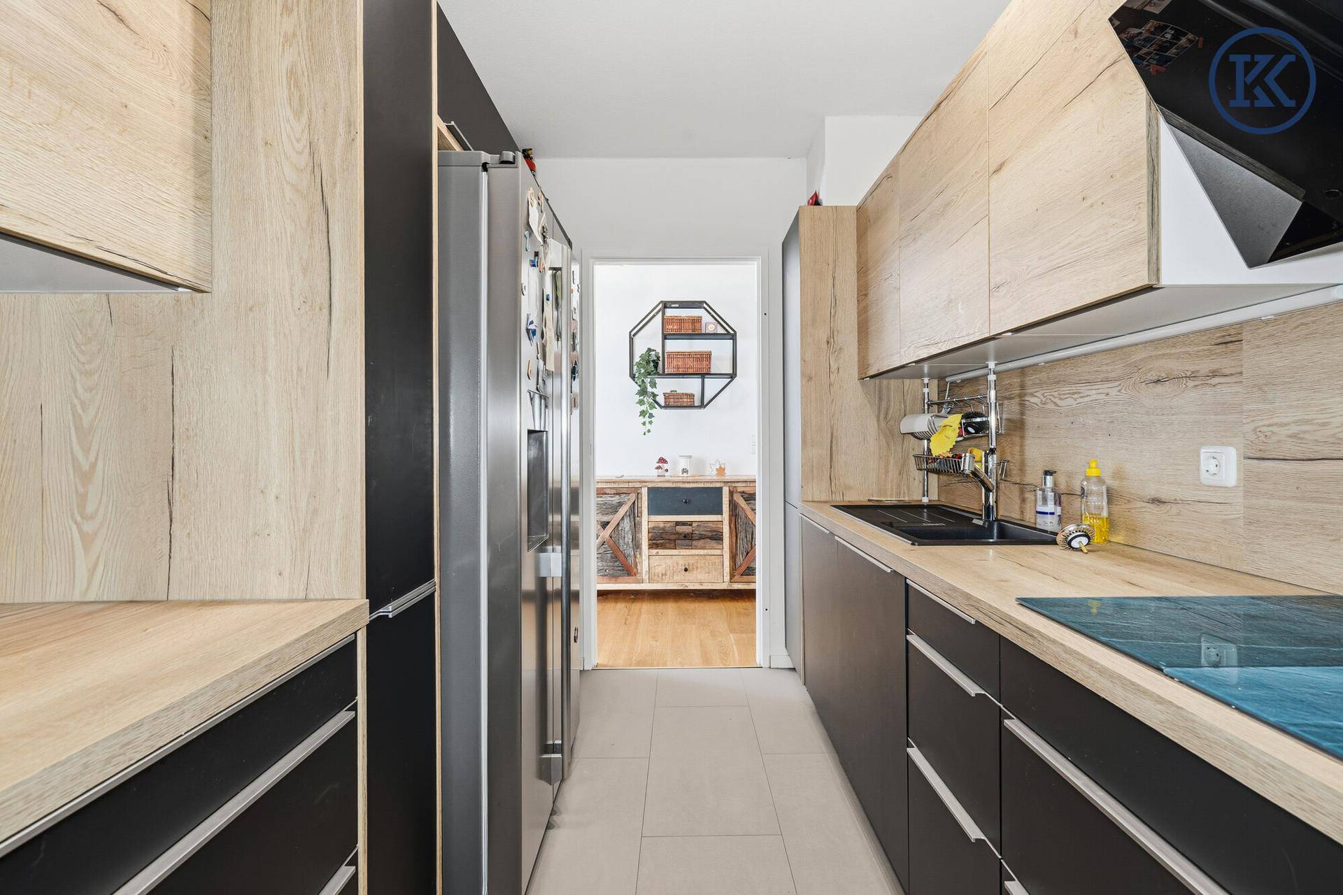 Gut ausgestattete Küche mit Holz- und Schwarzfronten, modernen Geräten und Fliesenboden.