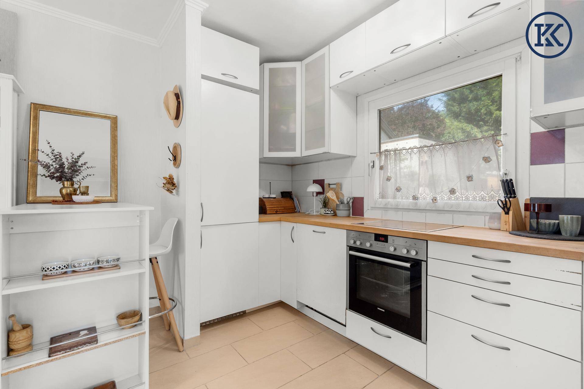 Funktionale Küche mit weißen Schränken, Kühlschrank und Holz-Arbeitsplatten.