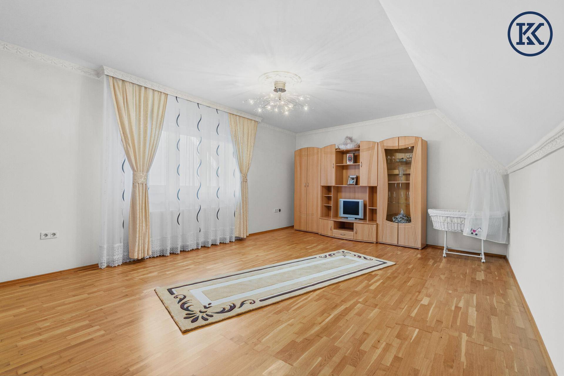 Helles Zimmer mit Parkettboden, Holzschrank und Fenster mit Blick nach draußen.
