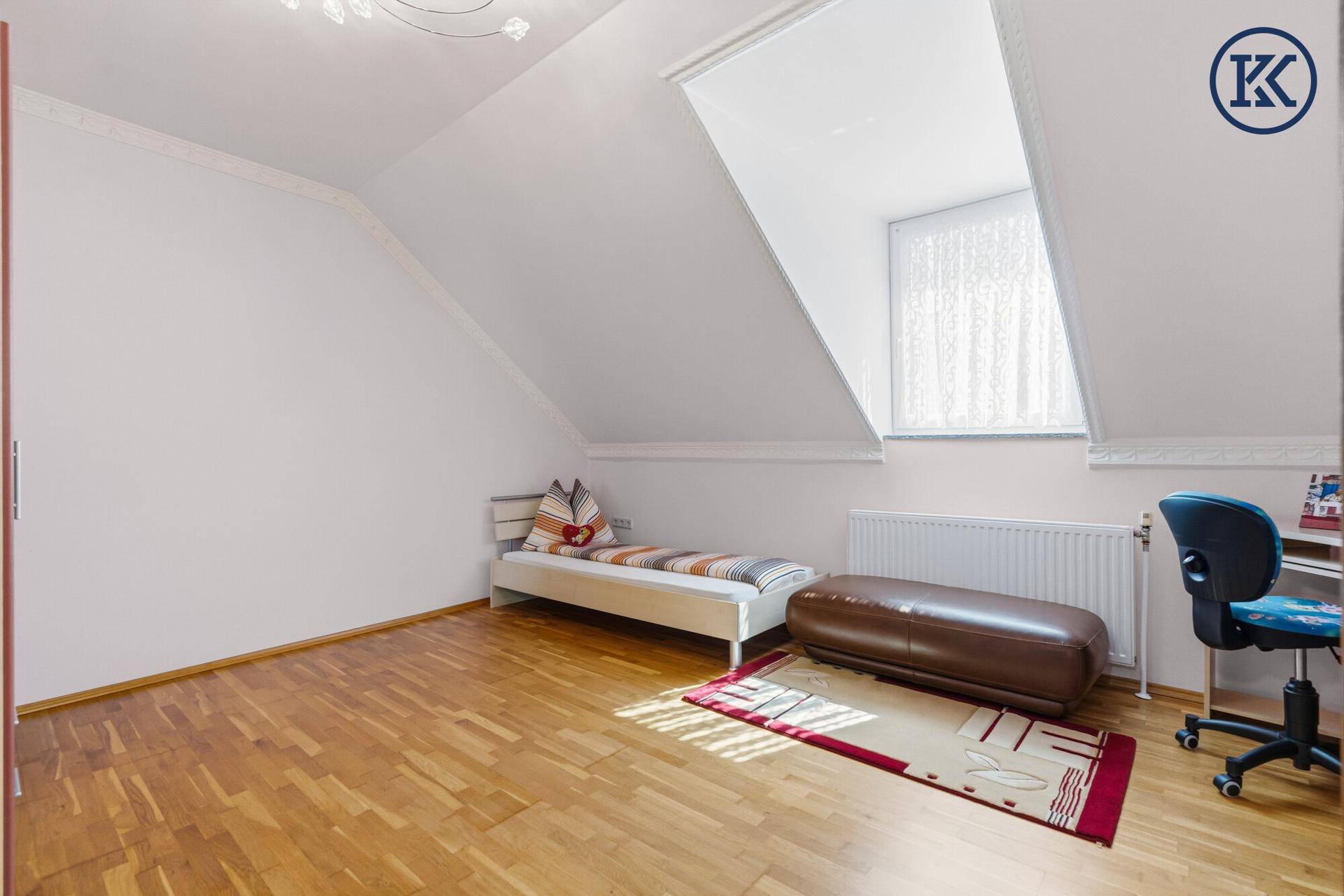 Kinderzimmer mit Parkettboden, Einzelbett, Schreibtisch und Dachfenster.