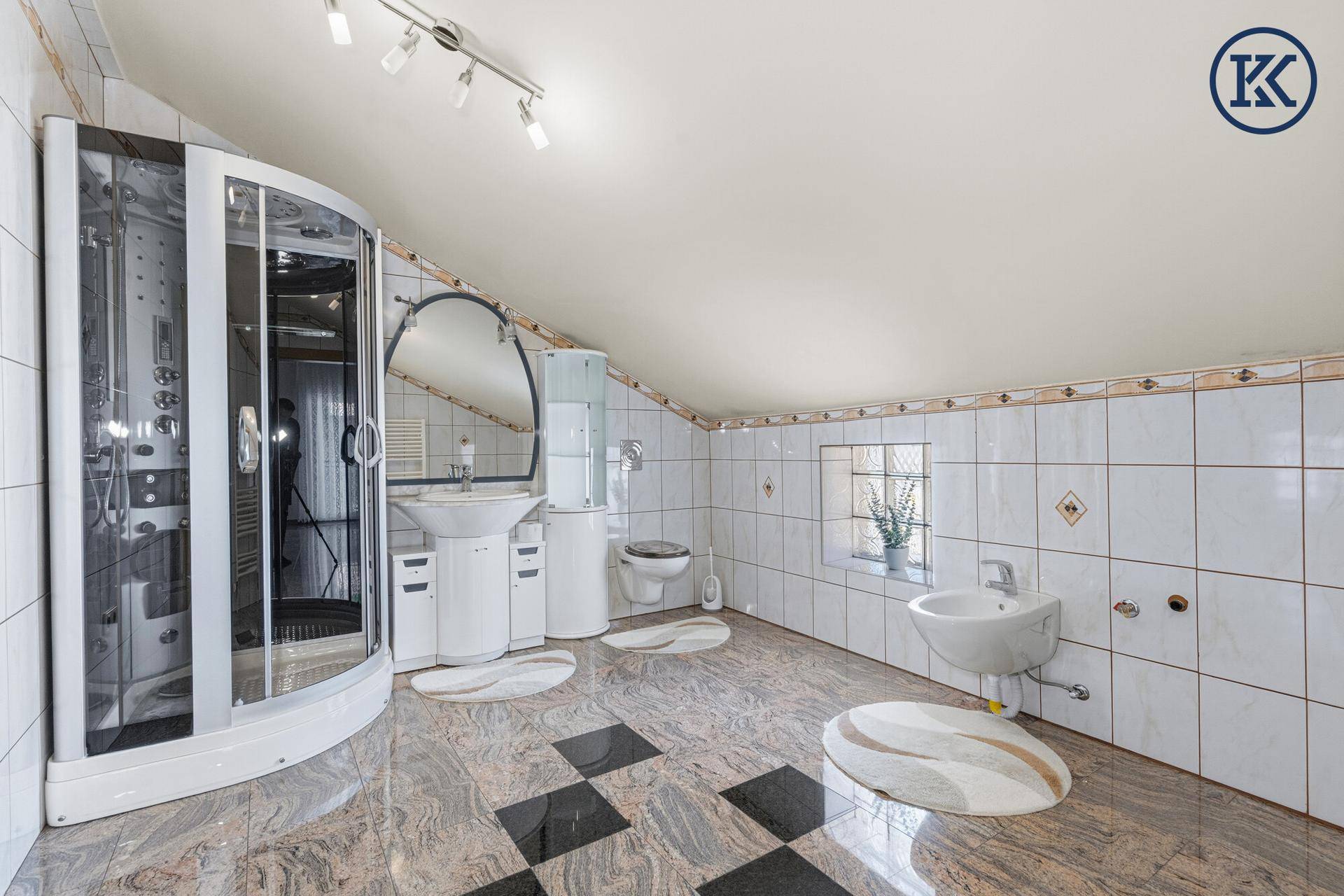 Geräumiges Badezimmer mit Dusche, Waschbecken, WC und Granitboden.