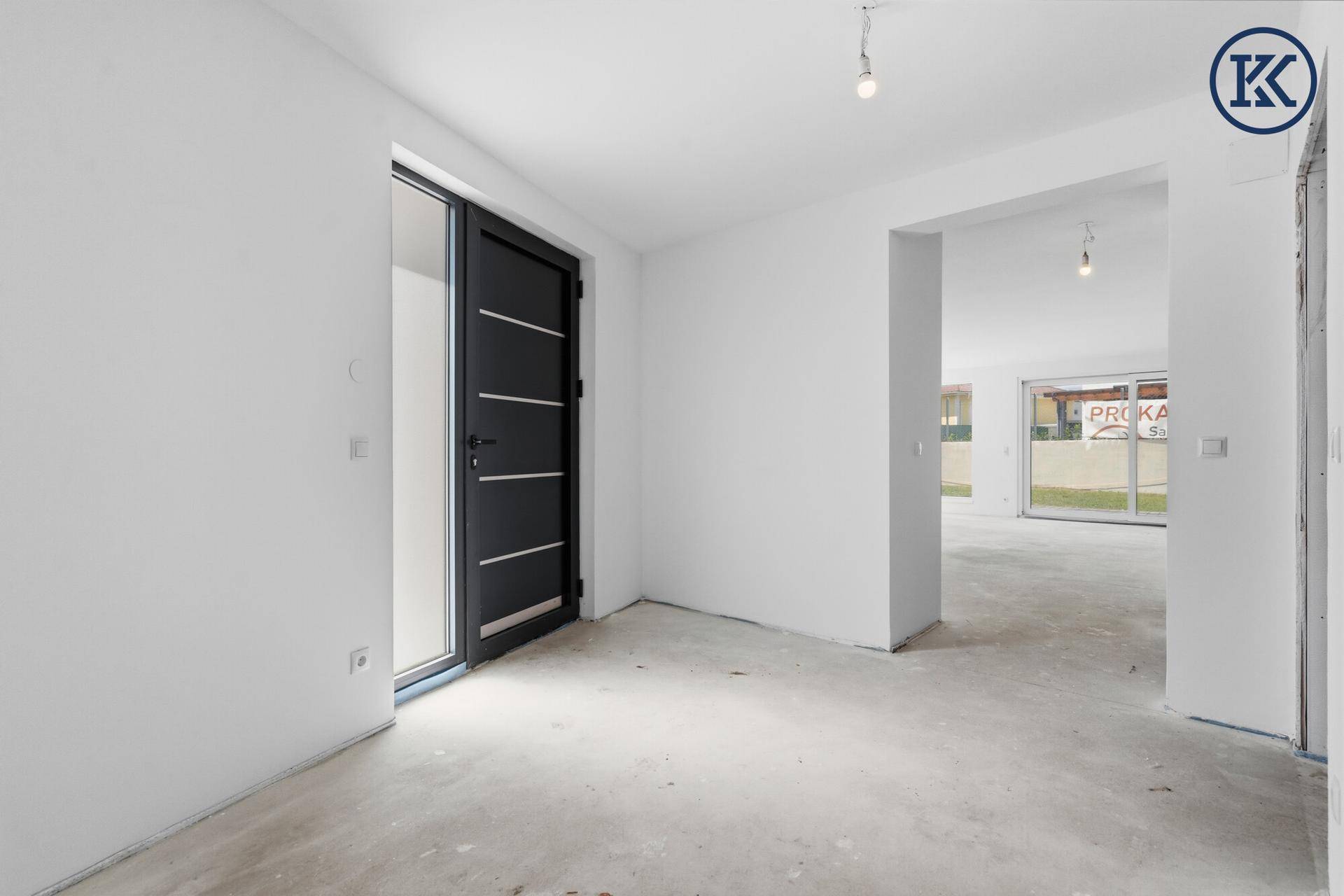 Heller Eingangsbereich mit moderner Haustür und Blick in den offenen Wohnbereich im Rohbau.