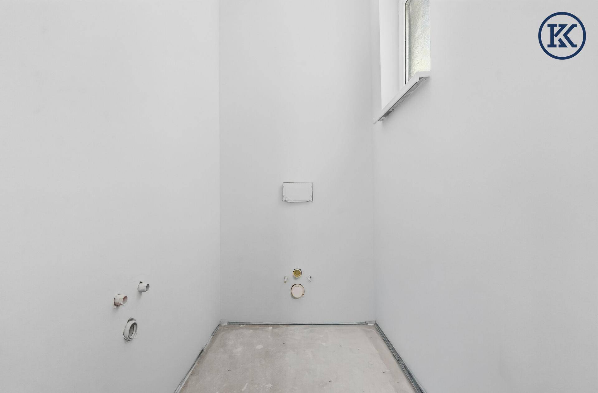 Unfertiges Gäste-WC mit Fenster und vorbereiteten Anschlüssen für Sanitäranlagen im Neubau.