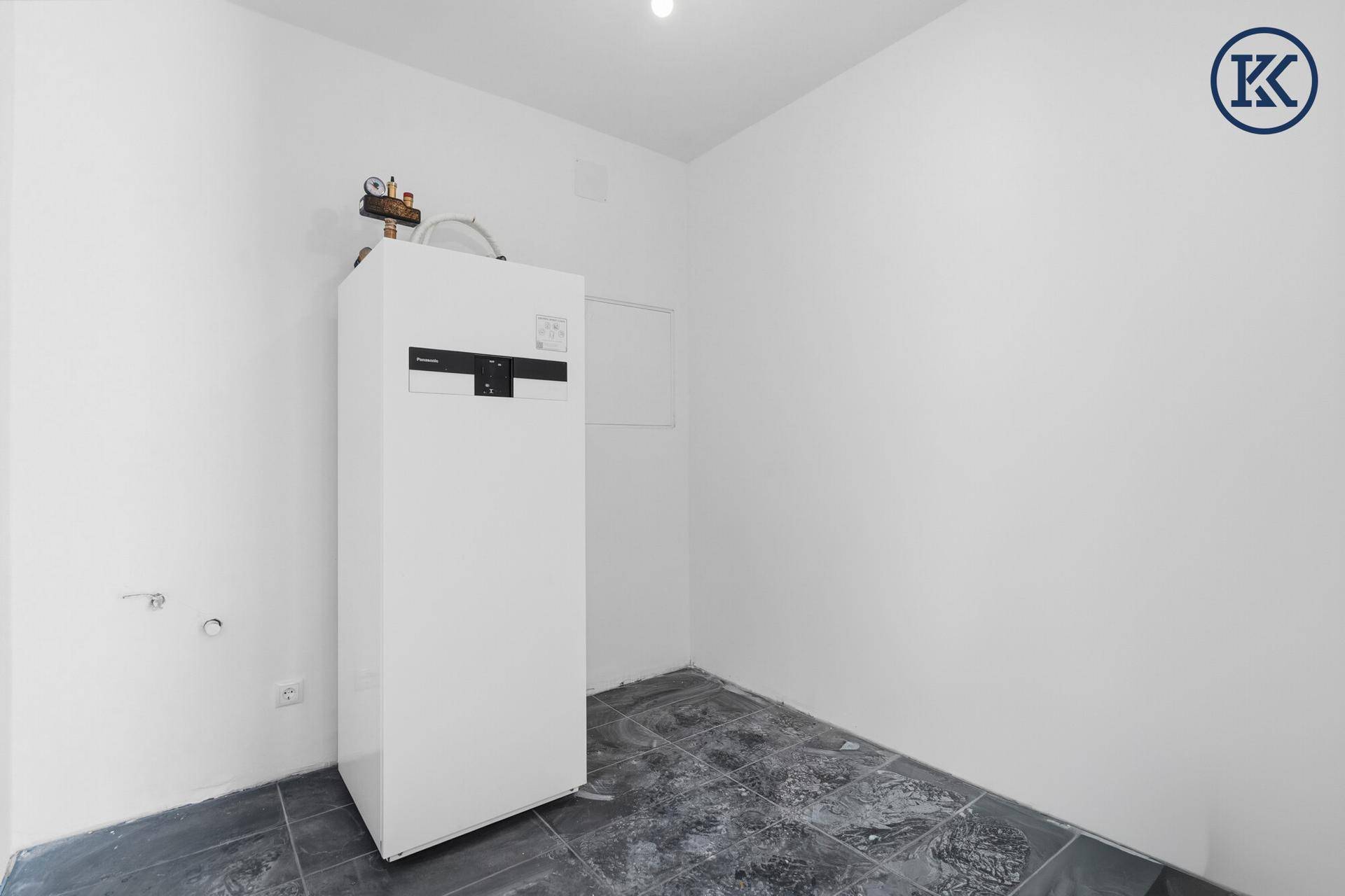 Hauswirtschaftsraum mit moderner Wärmepumpe und dunklen Fliesen auf dem Boden, funktional gestaltet.