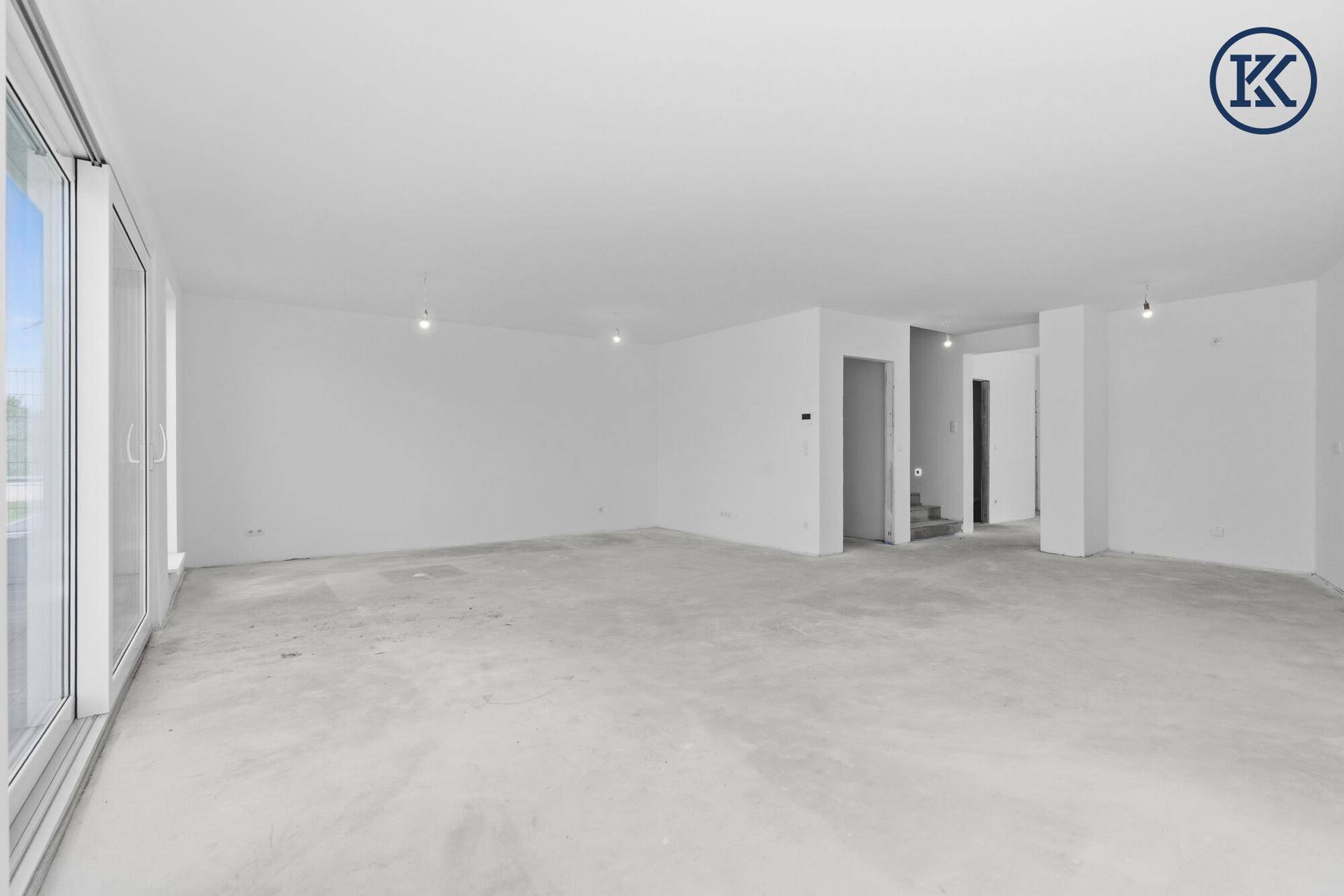 Großer, heller Wohnbereich im Rohbau mit Blick auf die zukünftigen Wohnräume und viel Platz.