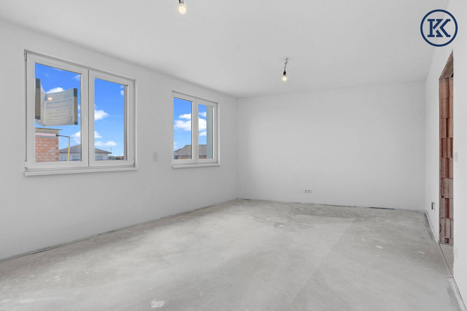 Heller, unfertiger Raum in einem Neubau mit großen Fenstern und Blick auf die Umgebung.
