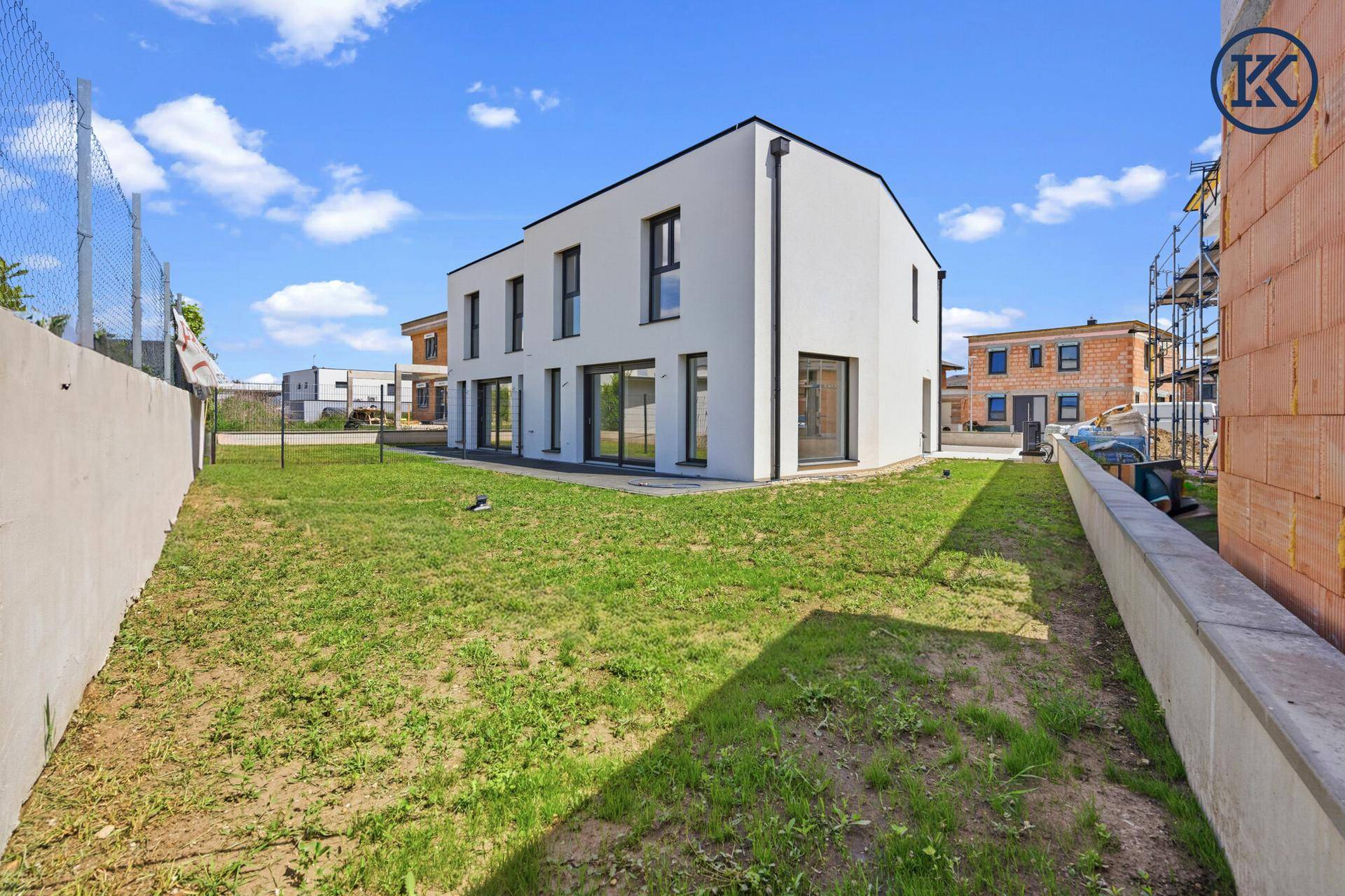 Weitläufiger Gartenbereich neben dem modernen Neubau mit Blick auf die umliegende Bebauung.