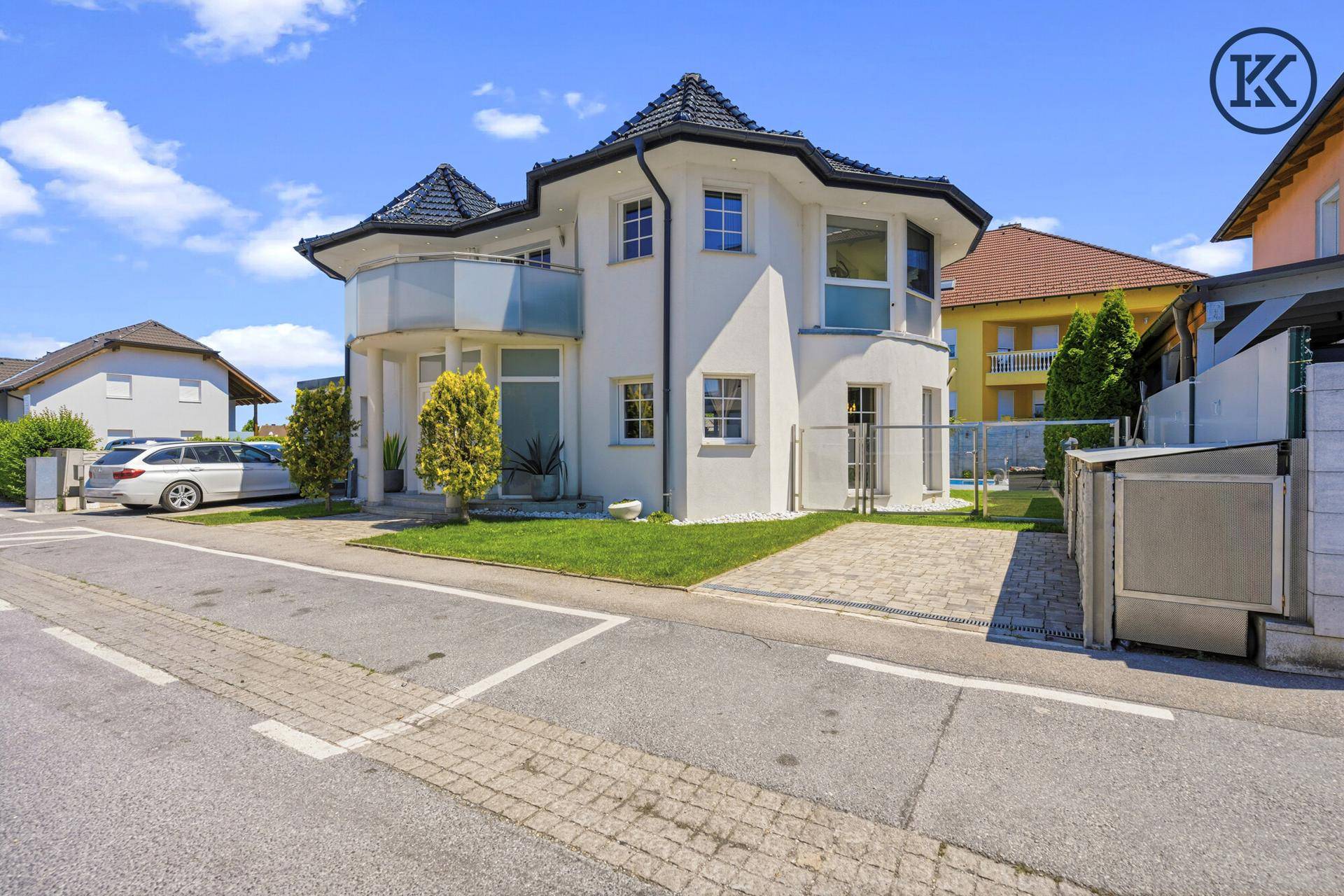 Stilvolle Villa mit moderner Architektur, großzügiger Einfahrt und gepflegter Grünfläche.