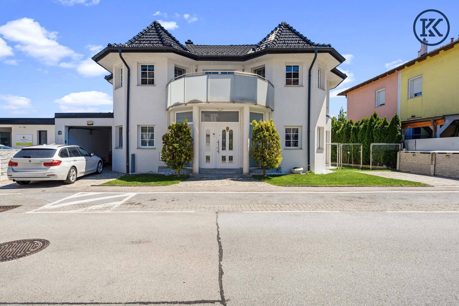 Elegante Villa von vorne mit gepflegtem Vorgarten und Doppelhaustür.