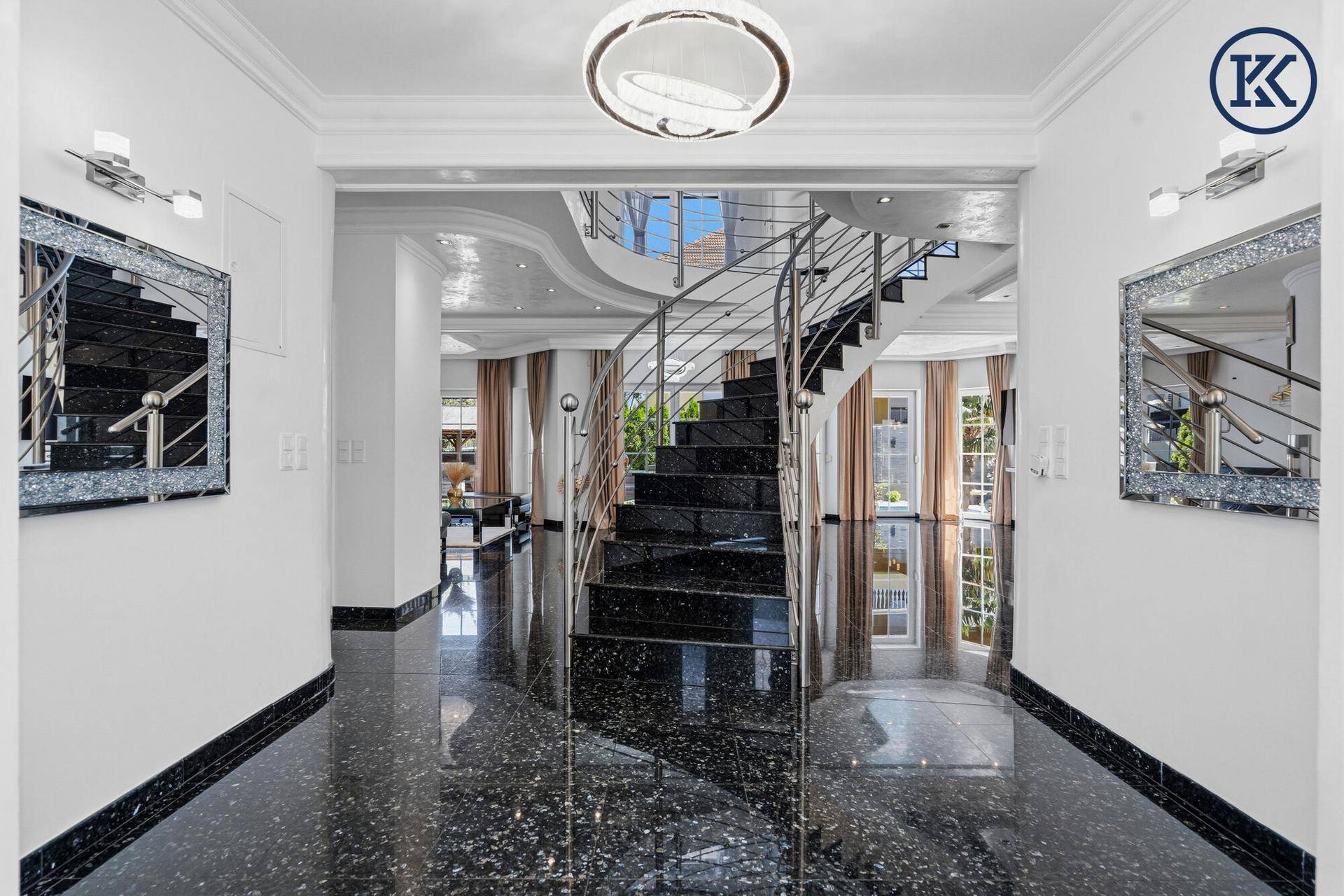 Großzügiger Flur mit eleganter schwarzer Marmortreppe und modernen Spiegellampen.