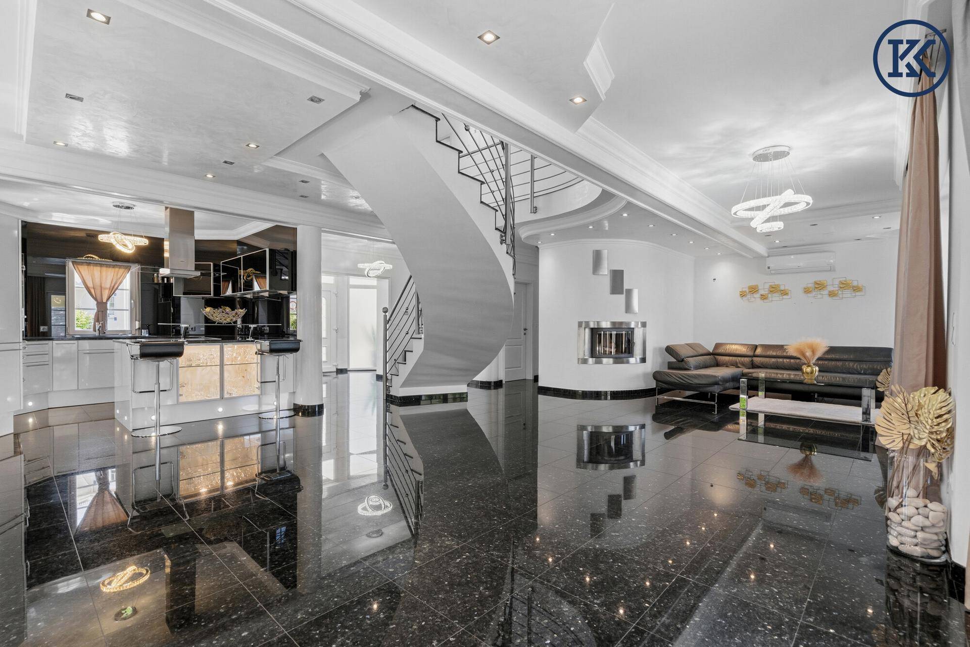 Weitläufiger offener Wohnbereich mit eleganter Treppe, Kamin und moderner Küche.