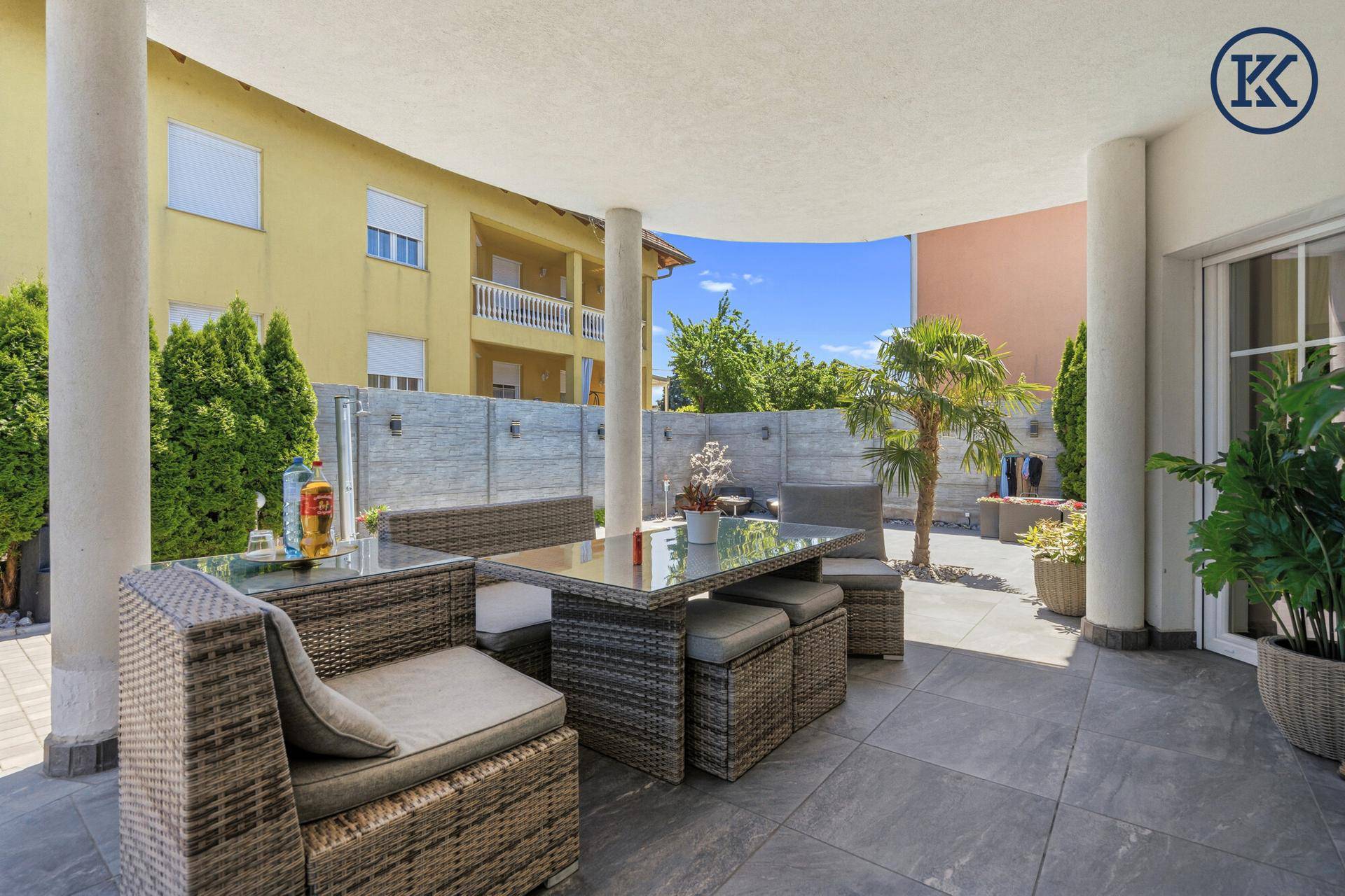 Überdachte Terrasse mit bequemen Loungemöbeln und Blick auf den Gartenbereich.