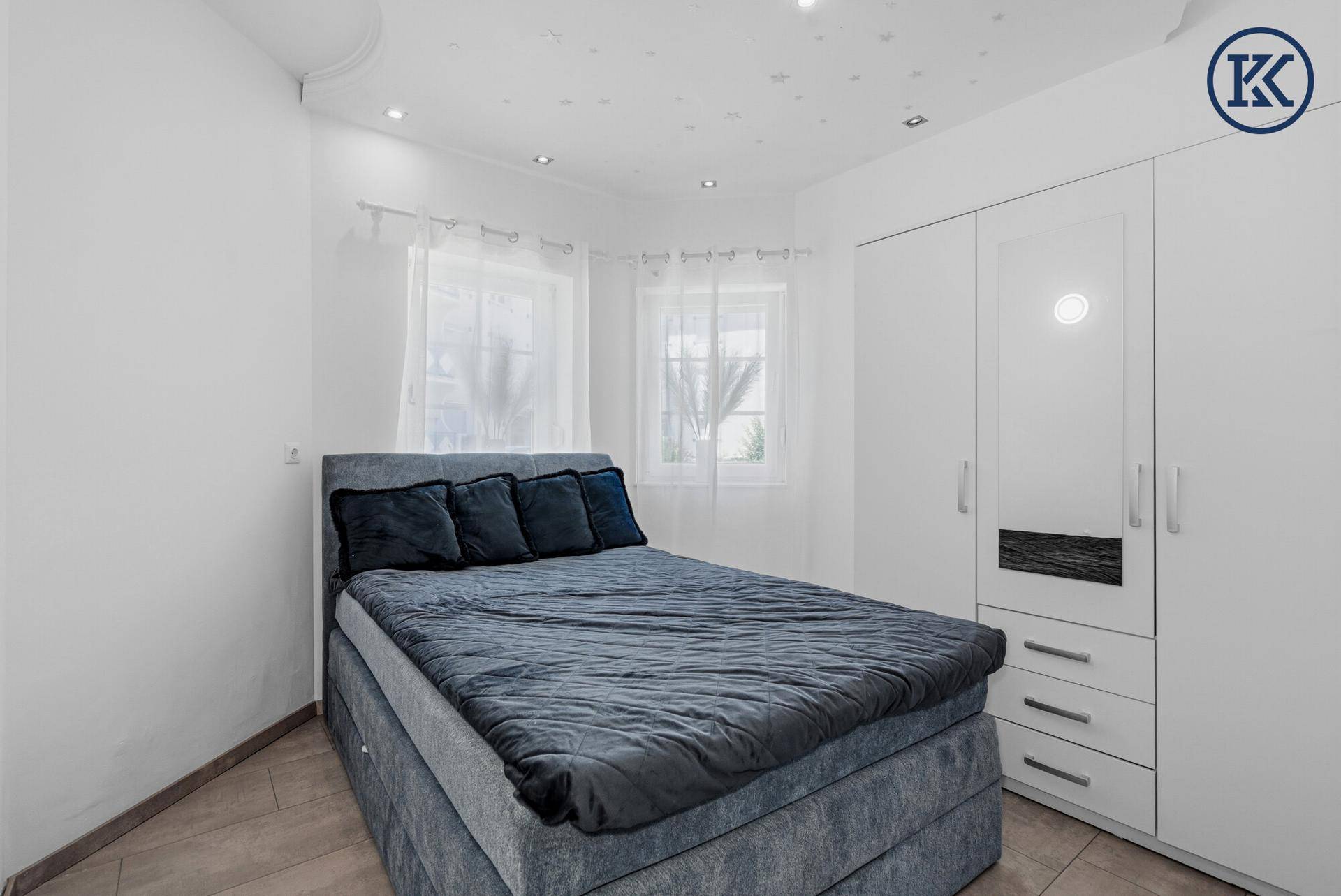 Gemütliches Schlafzimmer mit Doppelbett, weißem Kleiderschrank und Sternenlichtdecke.