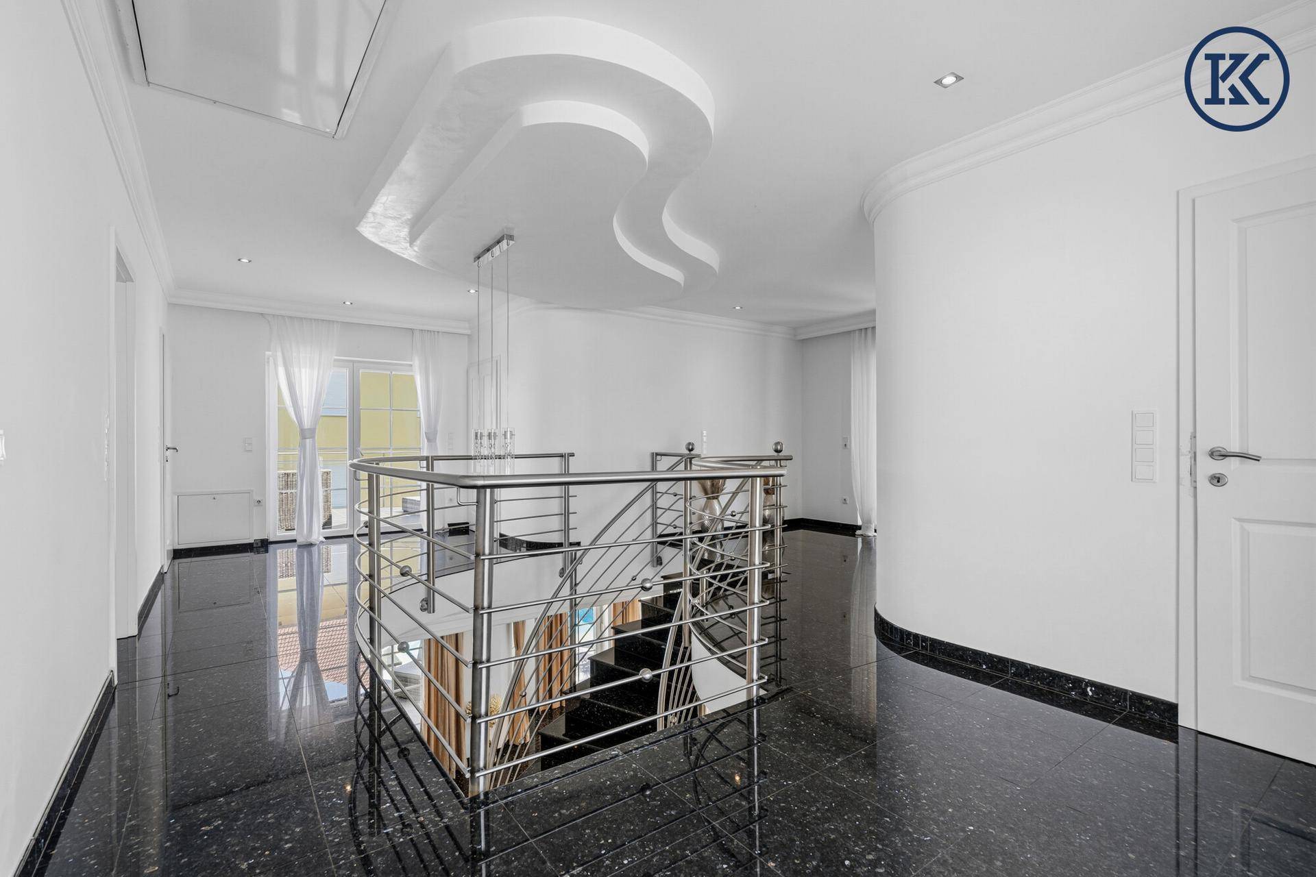 Heller Flur im Obergeschoss mit Blick auf die Treppe und dekorativer Deckenbeleuchtung.