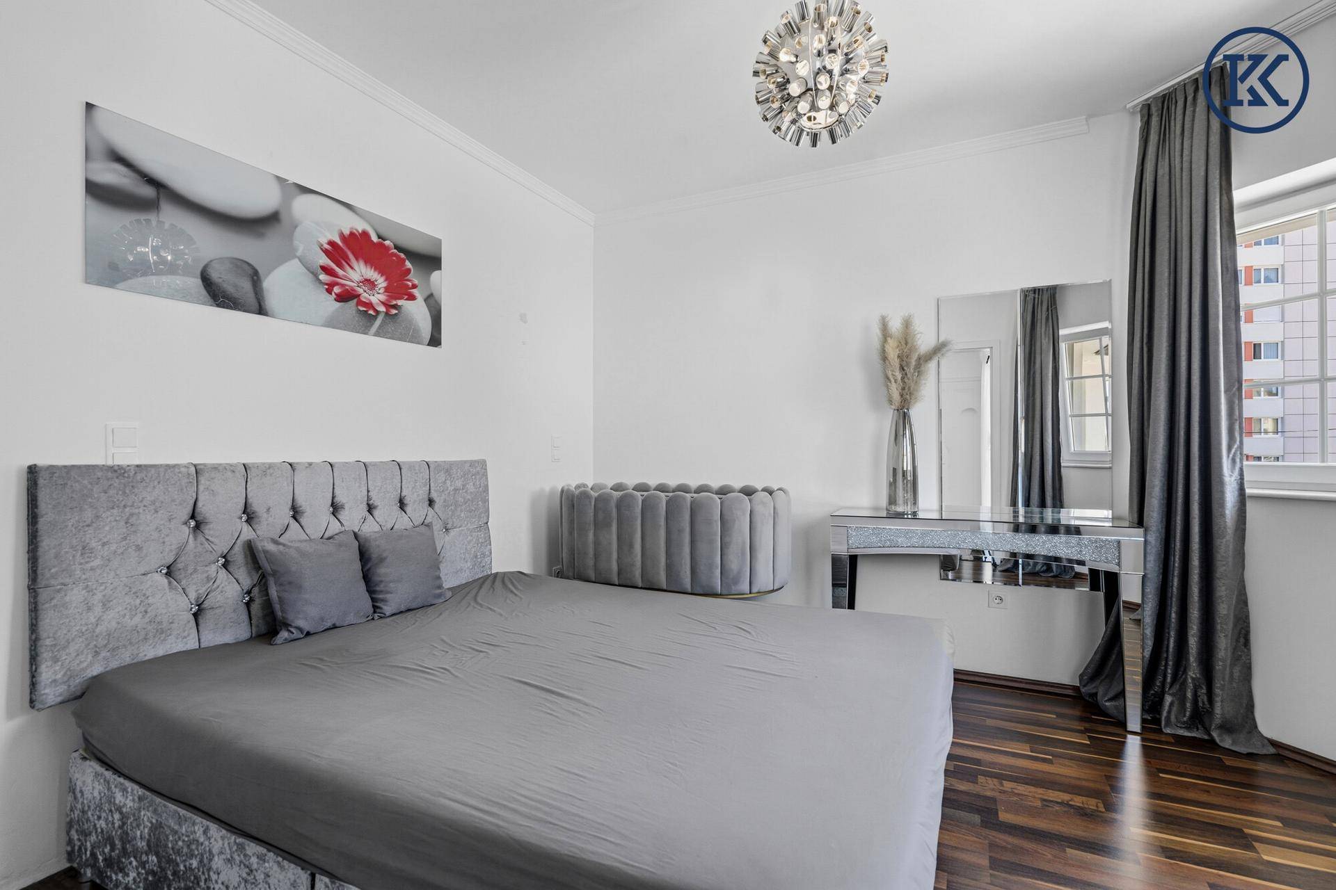 Komfortables Schlafzimmer mit großem Bett, Schminktisch und dunklem Holzfußboden.