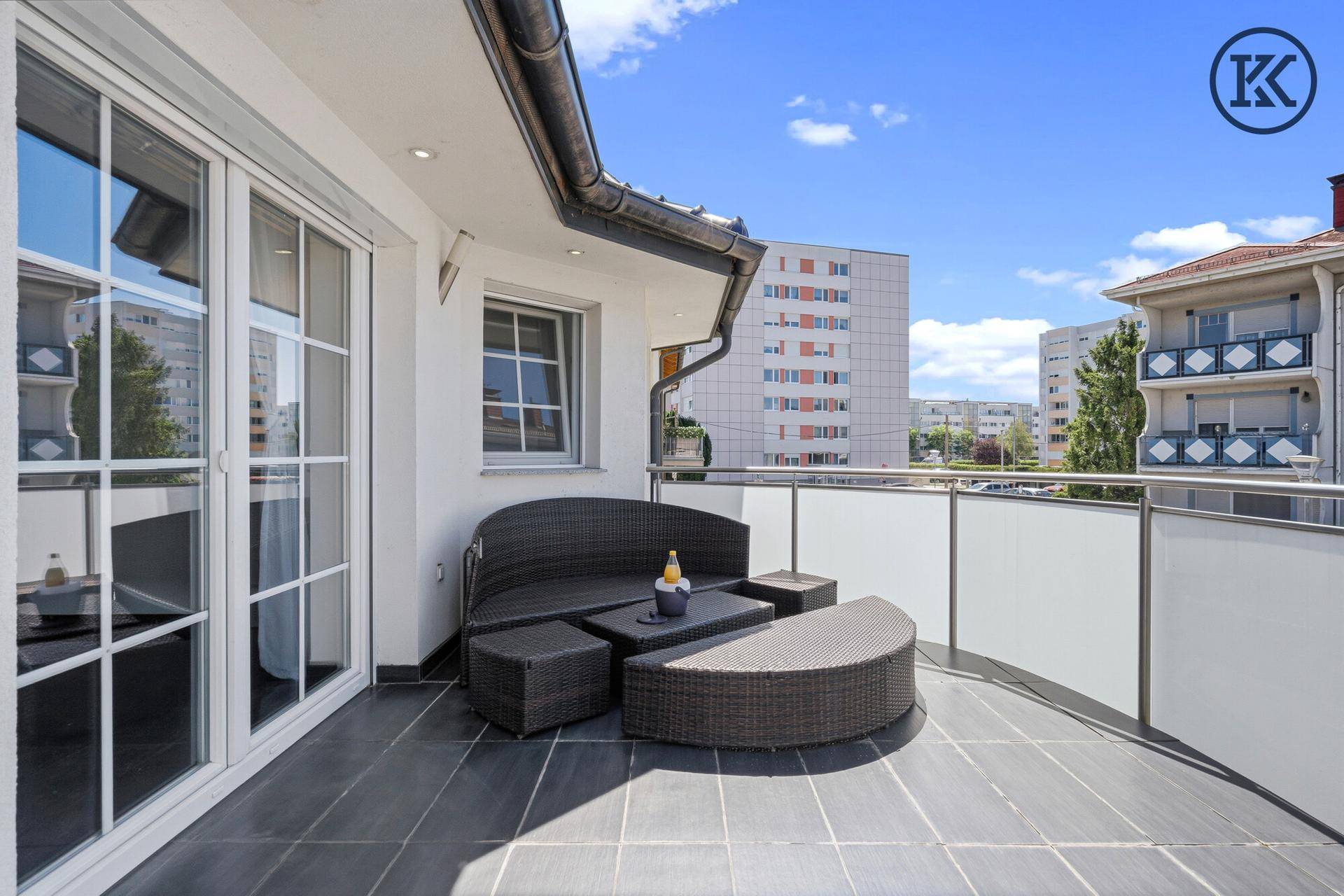 Geräumiger Balkon mit modernen Outdoor-Möbeln und Blick auf die umliegende Bebauung.