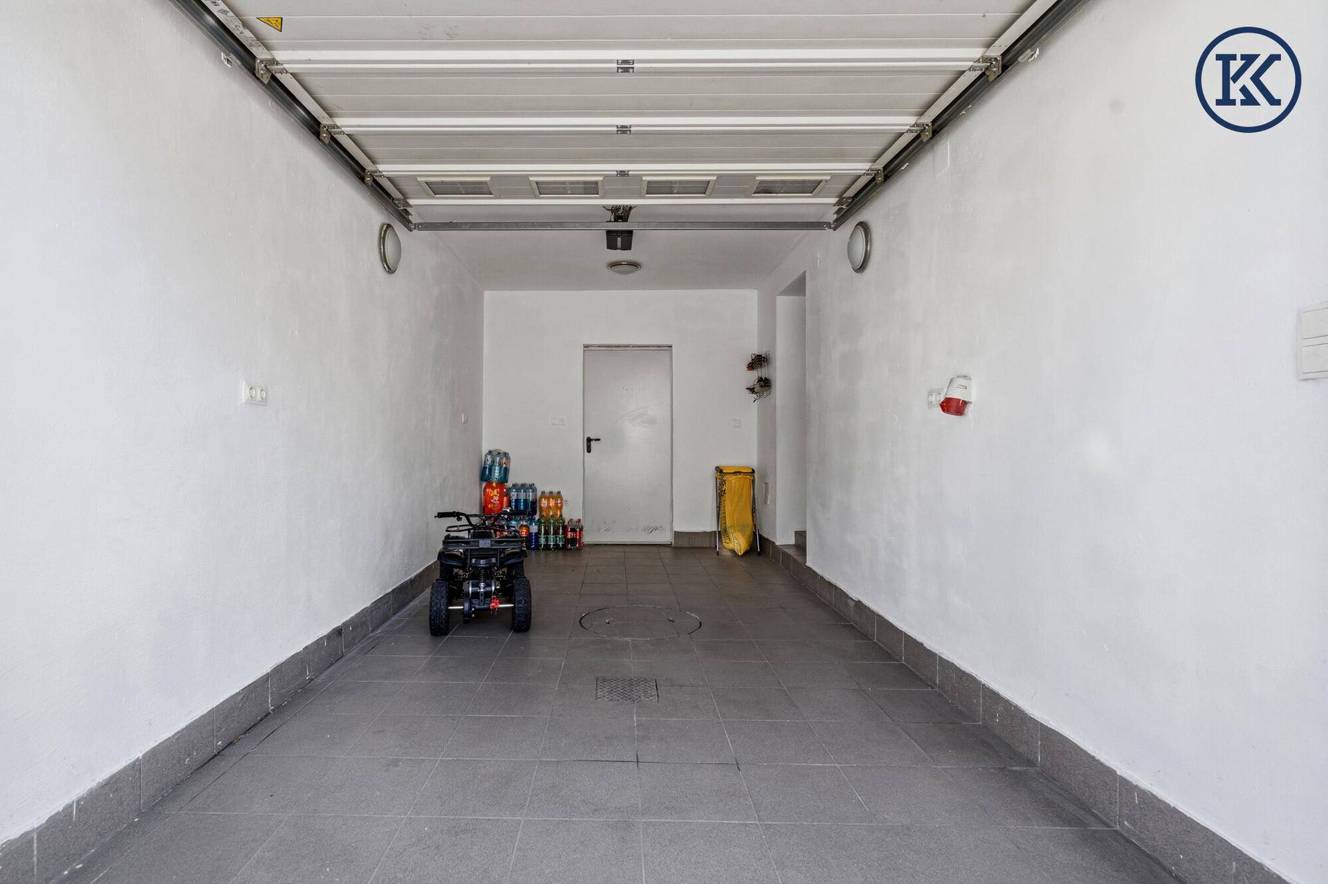 Geräumige und saubere Garage mit weiß gestrichenen Wänden und einem robusten Betonboden.