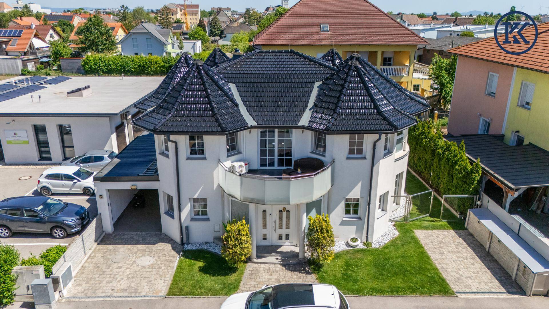 Elegantes Einfamilienhaus mit markantem Dach, Balkon und gepflegtem Vorgartenbereich.