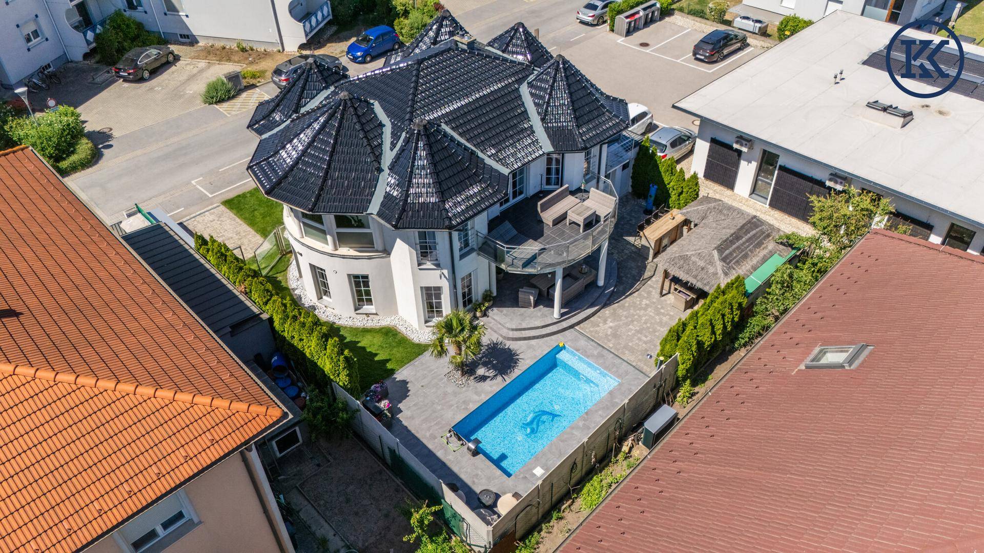 Weitläufige Luftaufnahme des Anwesens mit großem Pool und umliegender Wohnbebauung unter blauem Himmel.