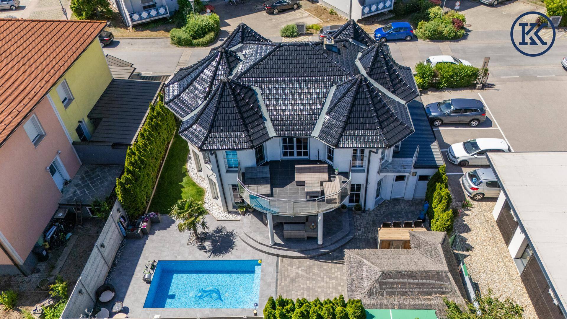 Luftaufnahme eines luxuriösen Hauses mit Pool, großer Terrasse und gepflegtem Gartenbereich.