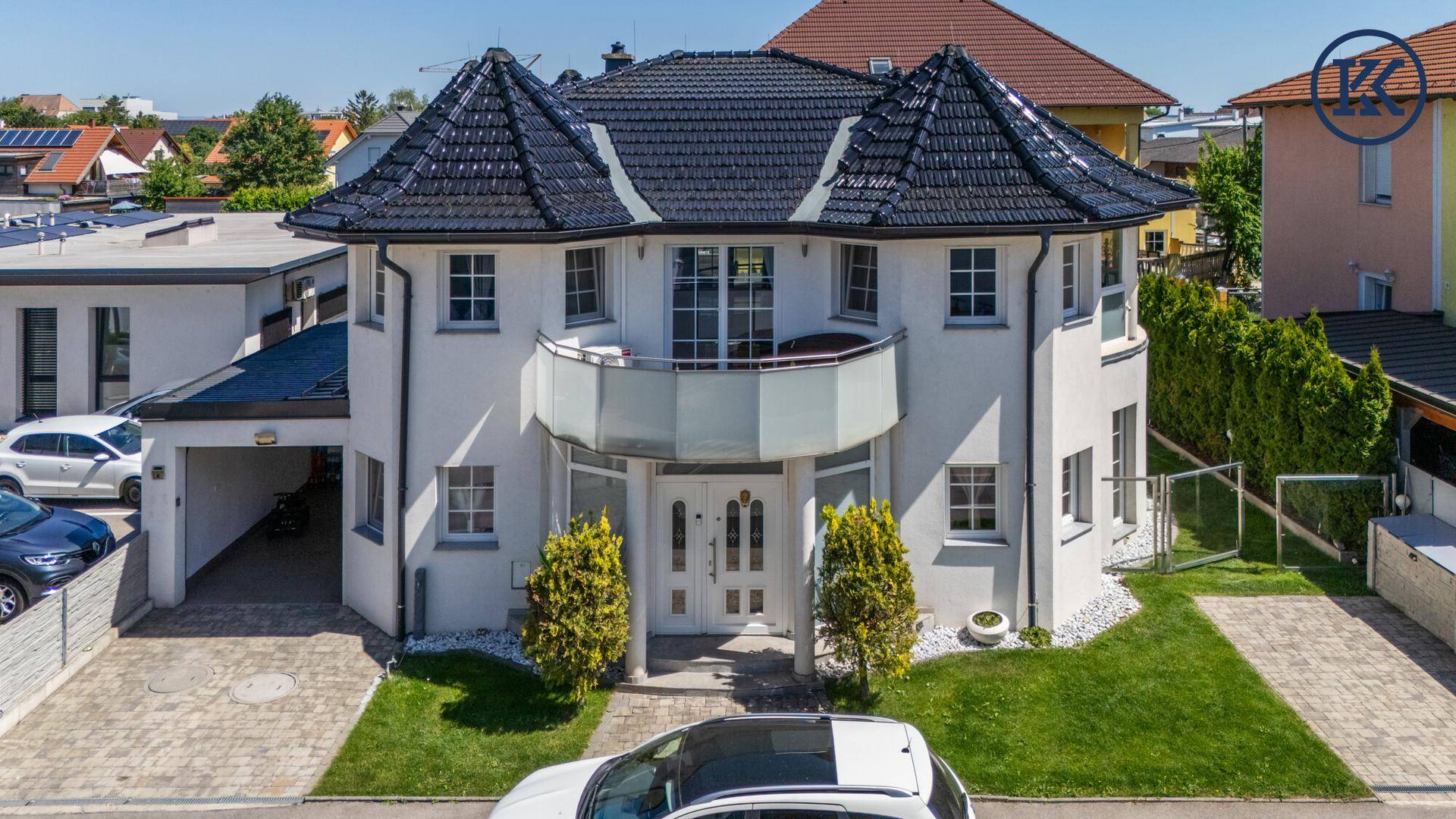 Attraktives Einfamilienhaus mit Balkon, Carport und gepflegter Grünfläche im Vorgartenbereich.