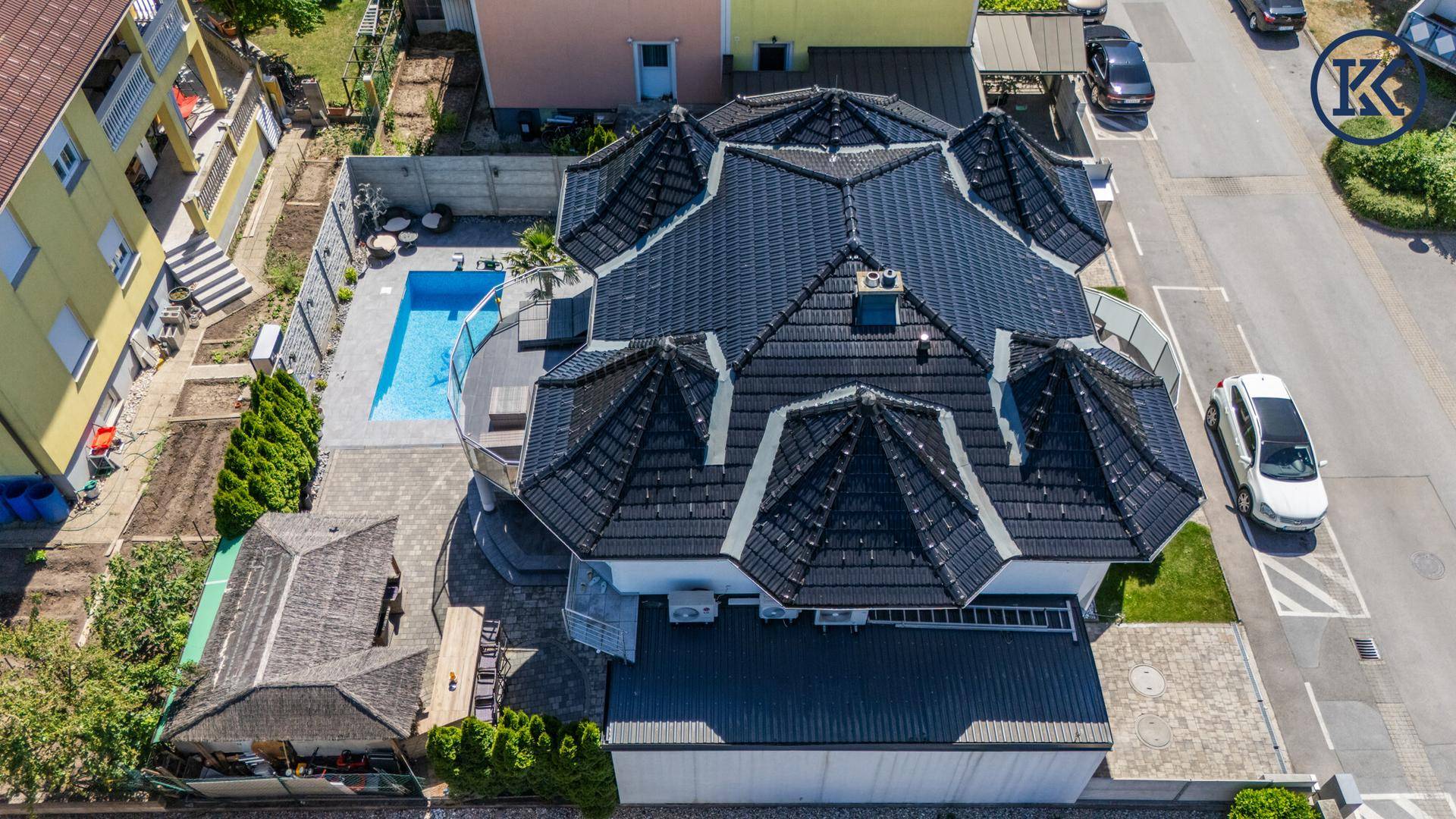 Gesamtansicht des Anwesens von oben mit Pool, Terrasse und Garten, umgeben von Nachbarhäusern.