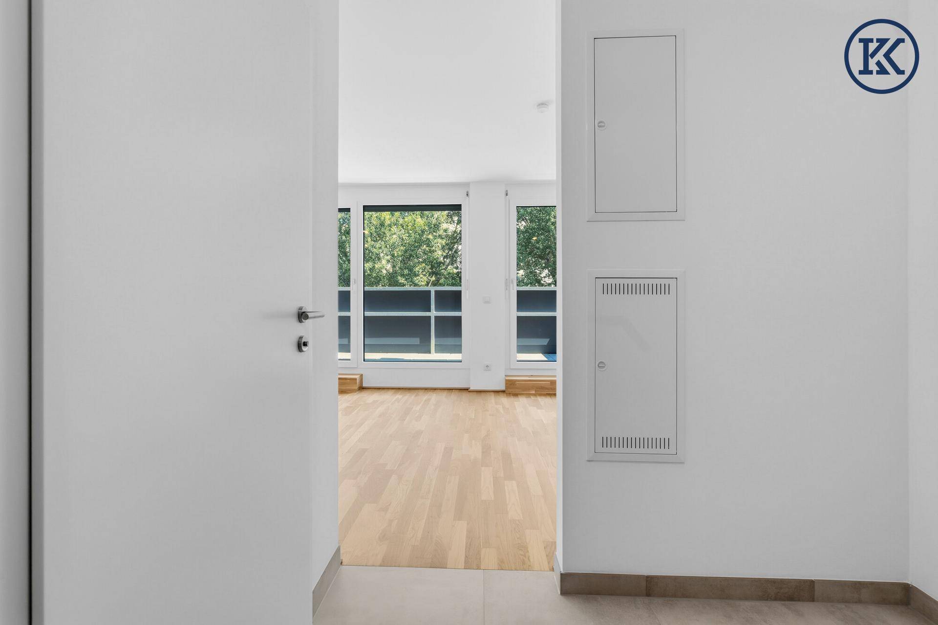 Eingangsbereich einer Wohnung mit hellem Parkettboden und Blick auf den Wohnbereich.