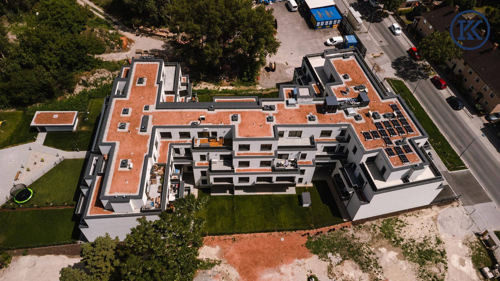 Luftaufnahme des großen Wohnkomplexes mit Flachdächern, Grünflächen und Solaranlagen.
