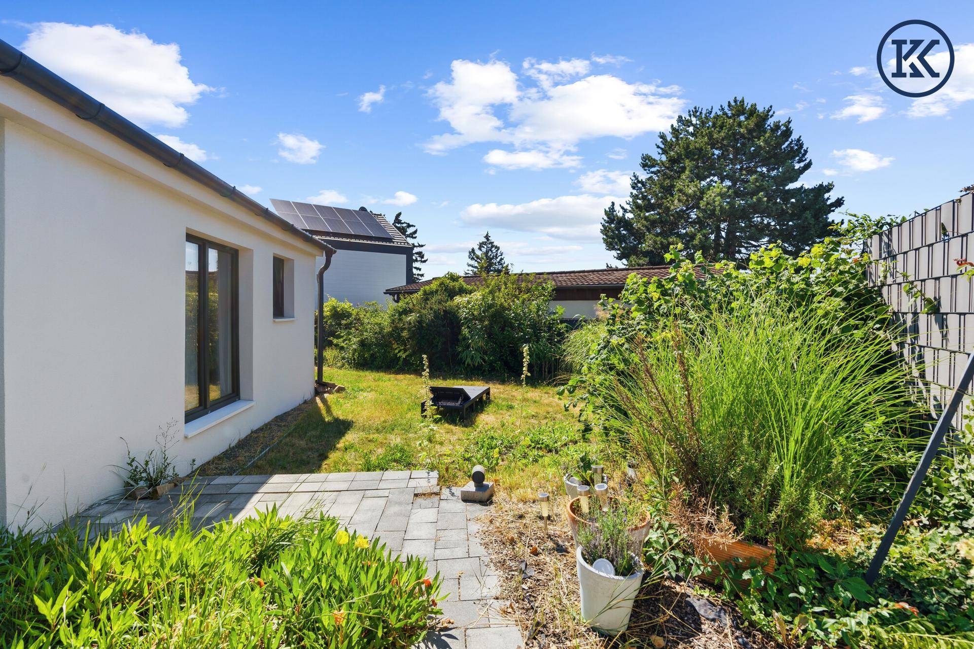 Gepflegter Gartenbereich mit Steinplattenweg, üppiger Vegetation und Blick auf das Haus.