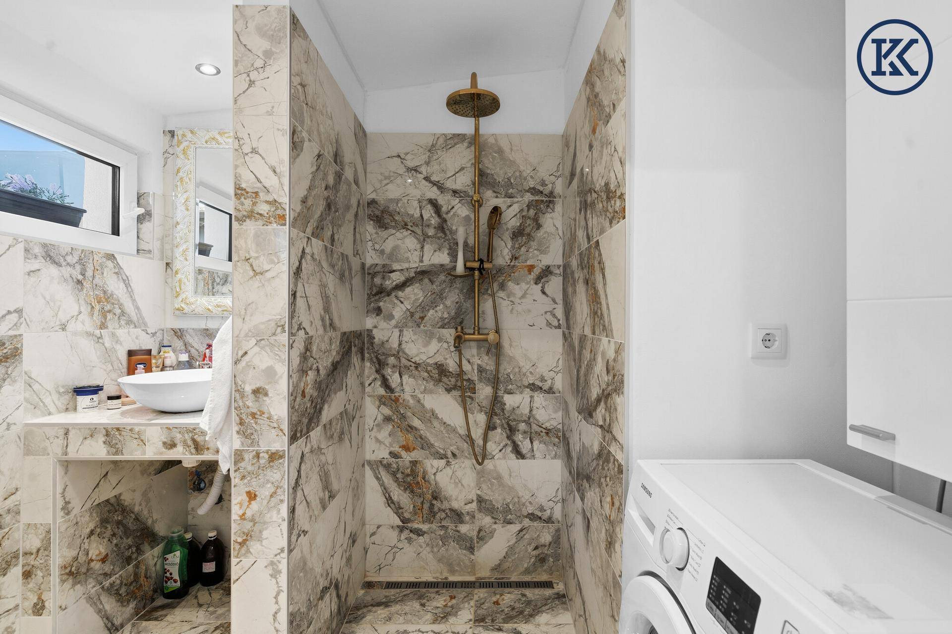 Modernes Badezimmer mit begehbarer Dusche, Marmorfliesen und Waschmaschine.