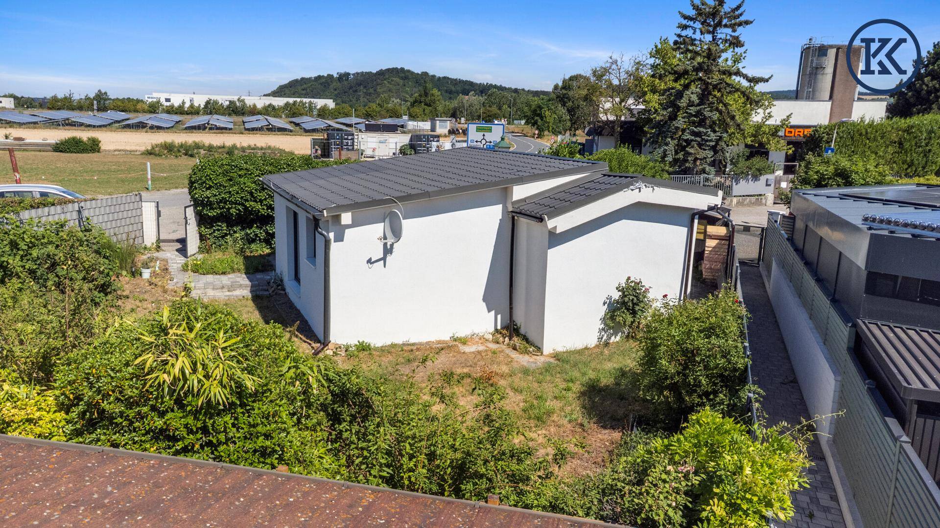 Luftaufnahme des Hauses mit Garten und Blick auf ein Feld mit Solaranlagen in der Ferne.