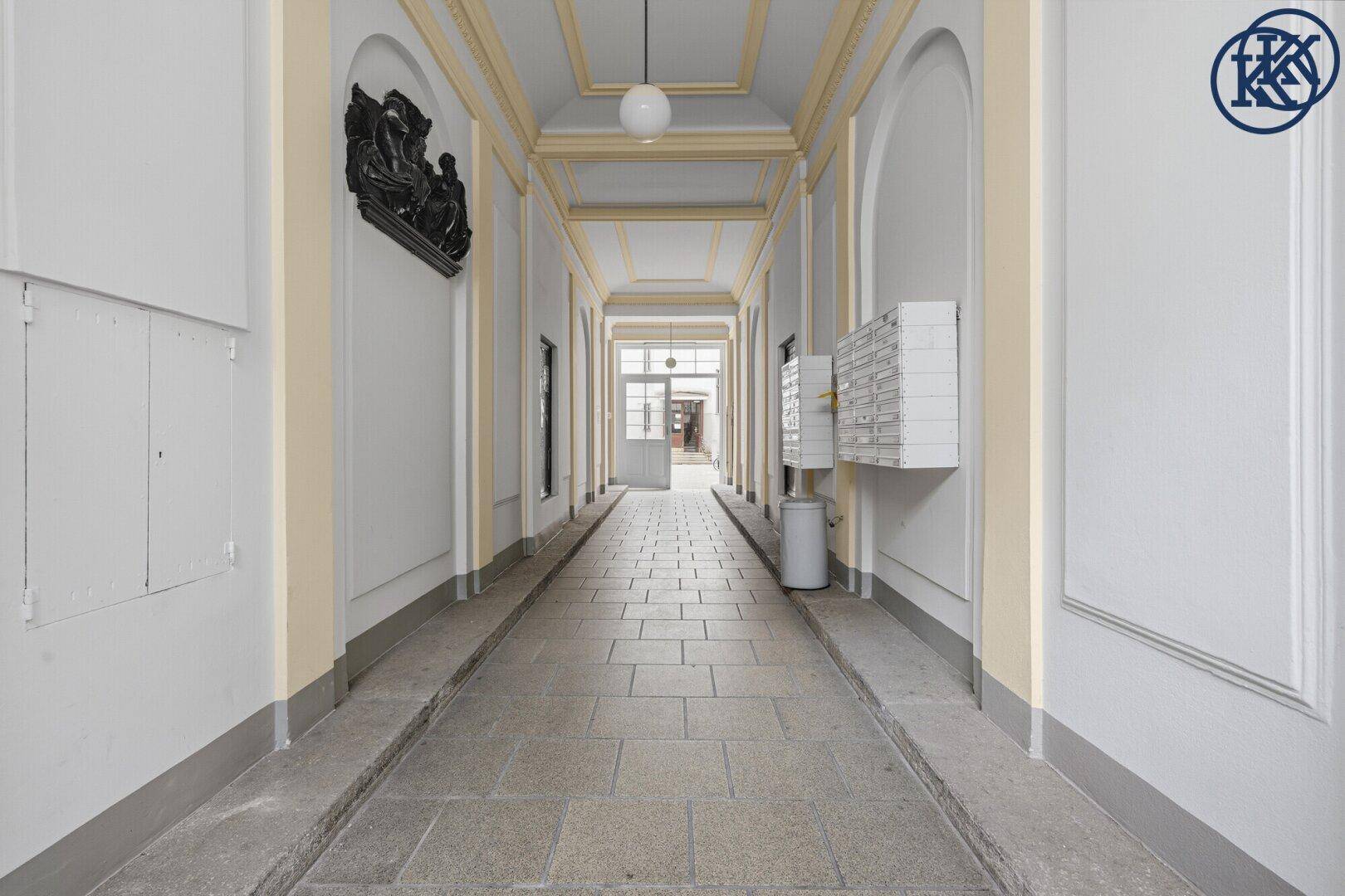 Historischer Durchgang mit Steinboden, Stuckdecken und Briefkästen an den Wänden.